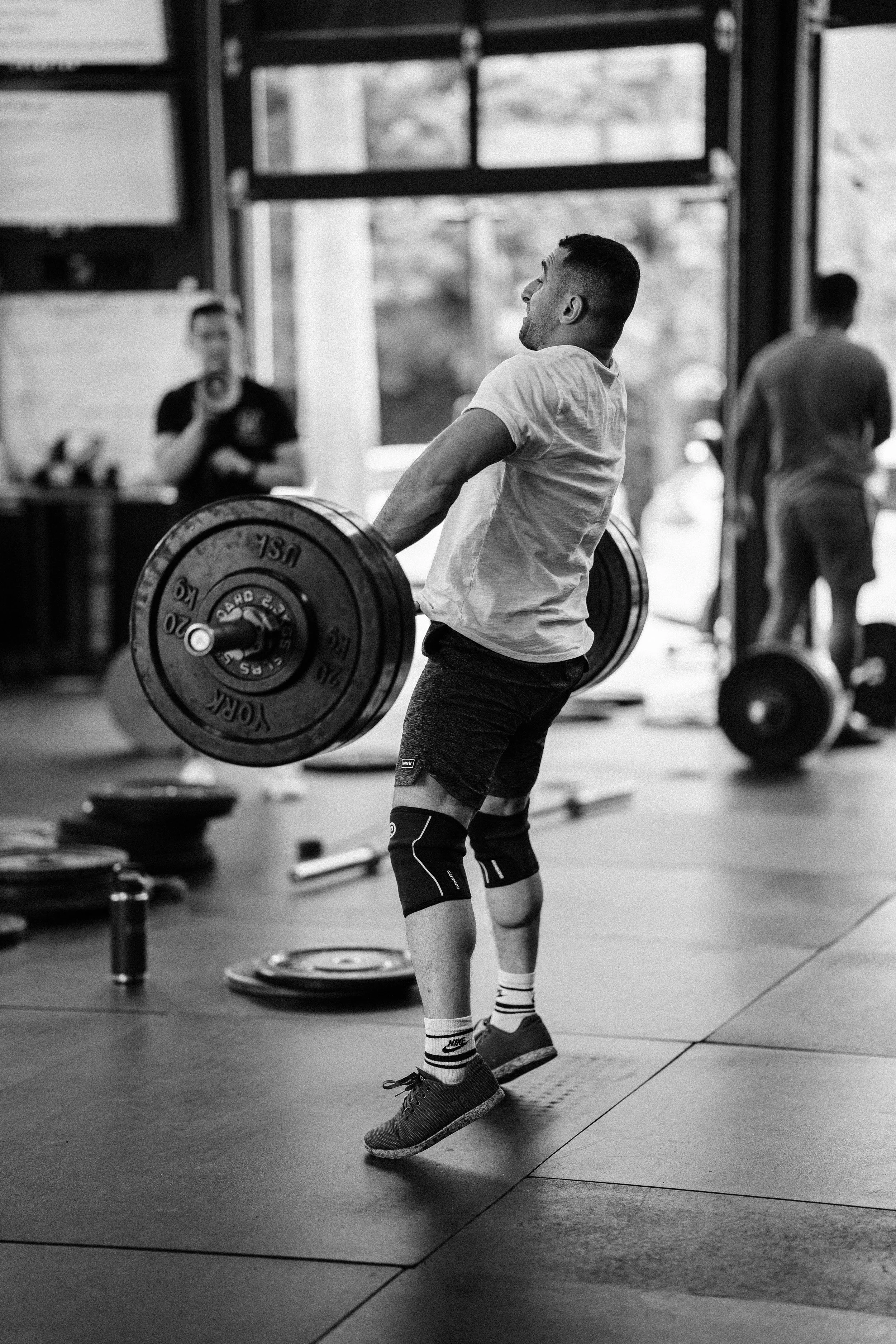 A man lifting a barbell with weights in a gym.