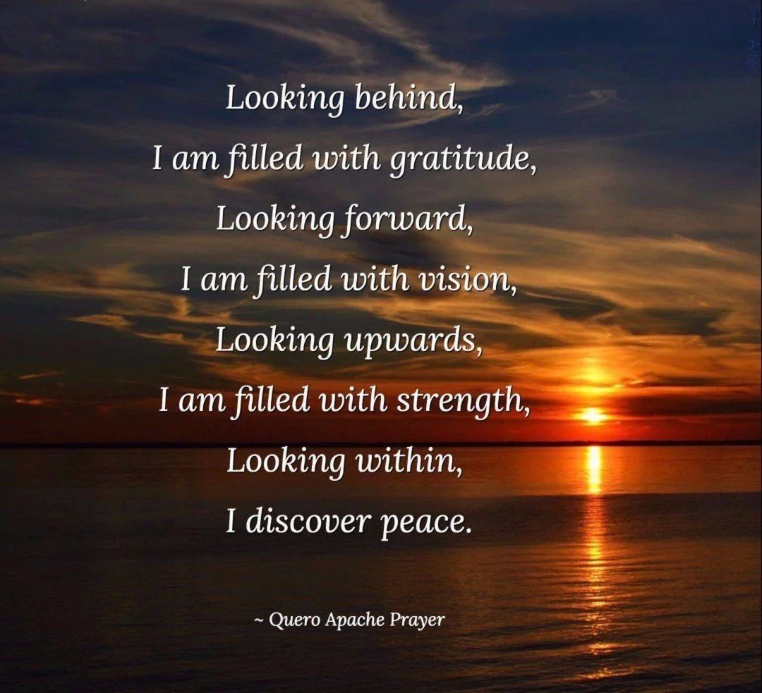 A sunset over a body of water with a colorful sky, featuring a quote about gratitude, vision, strength, and peace from the Quero Apache Prayer.