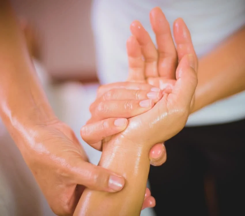 Hands being massaged or cared for, possibly at a spa or therapeutic setting.