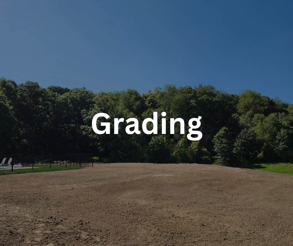 An empty dirt field with a line of trees in the background and a clear blue sky above. The word "Grading" is written in large white letters across the center.