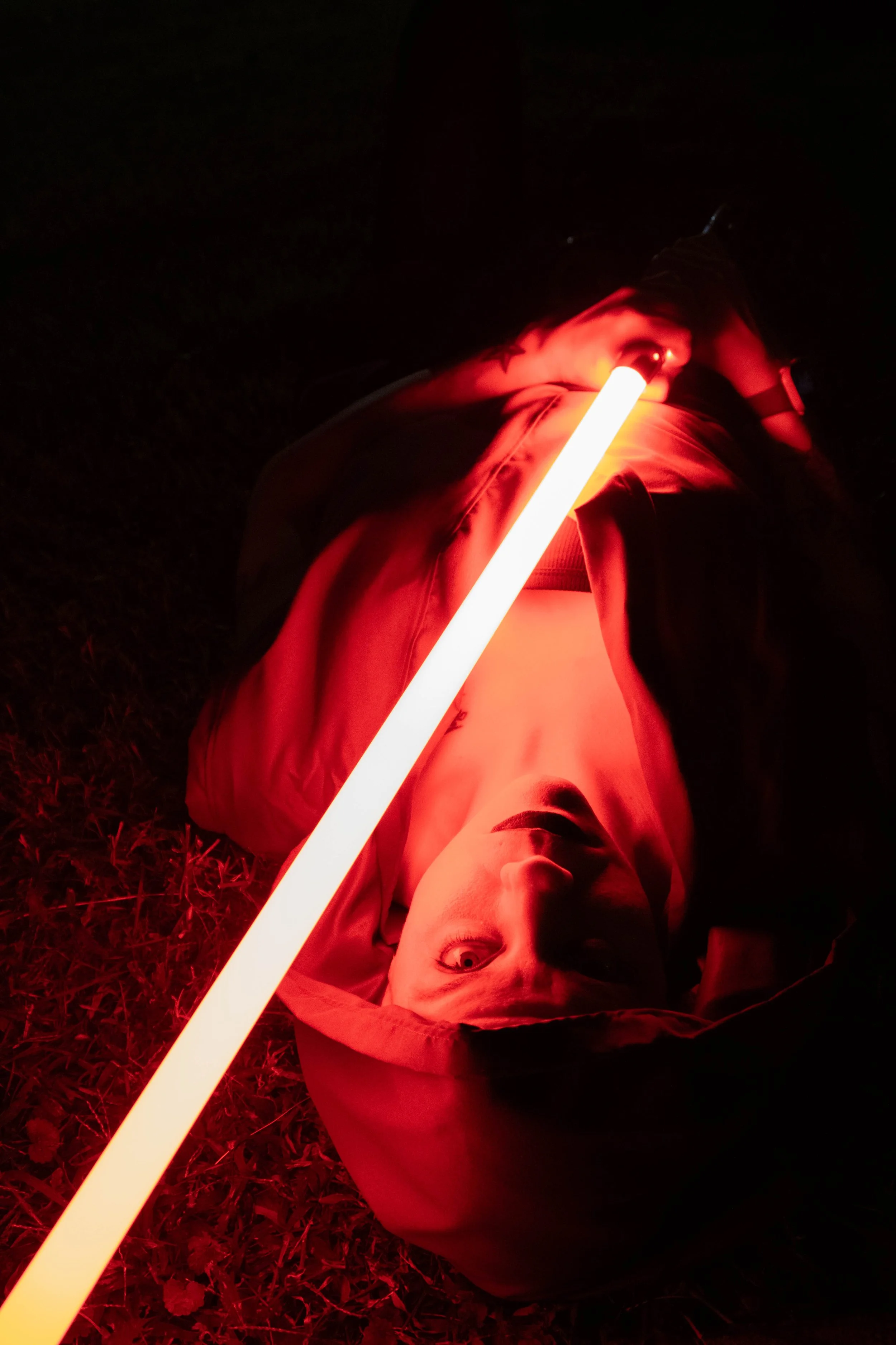 Artistic photo of a woman cosplaying as a Sith with a red lightsaber
