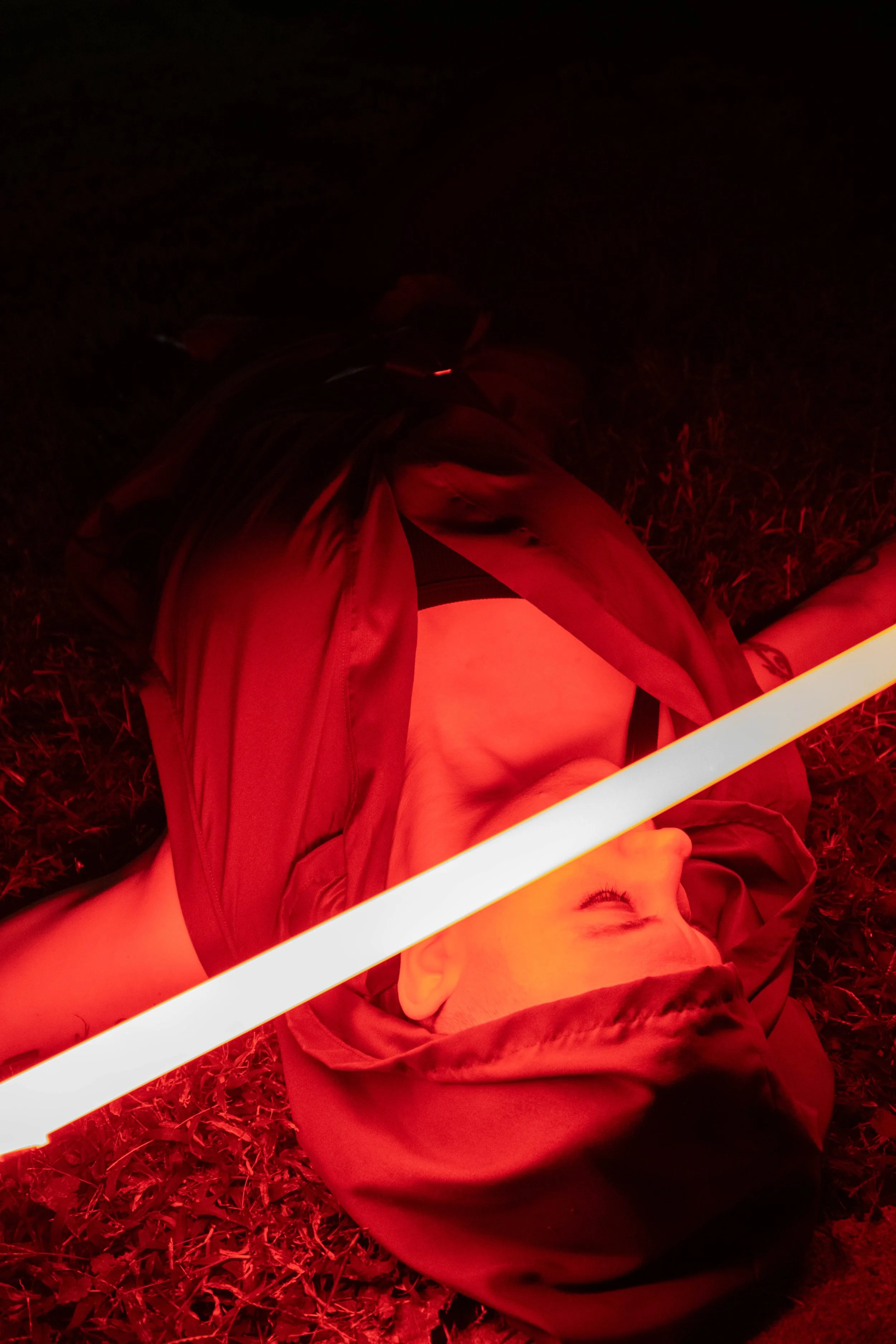 Artistic photo of a woman cosplaying as a Sith with a red lightsaber