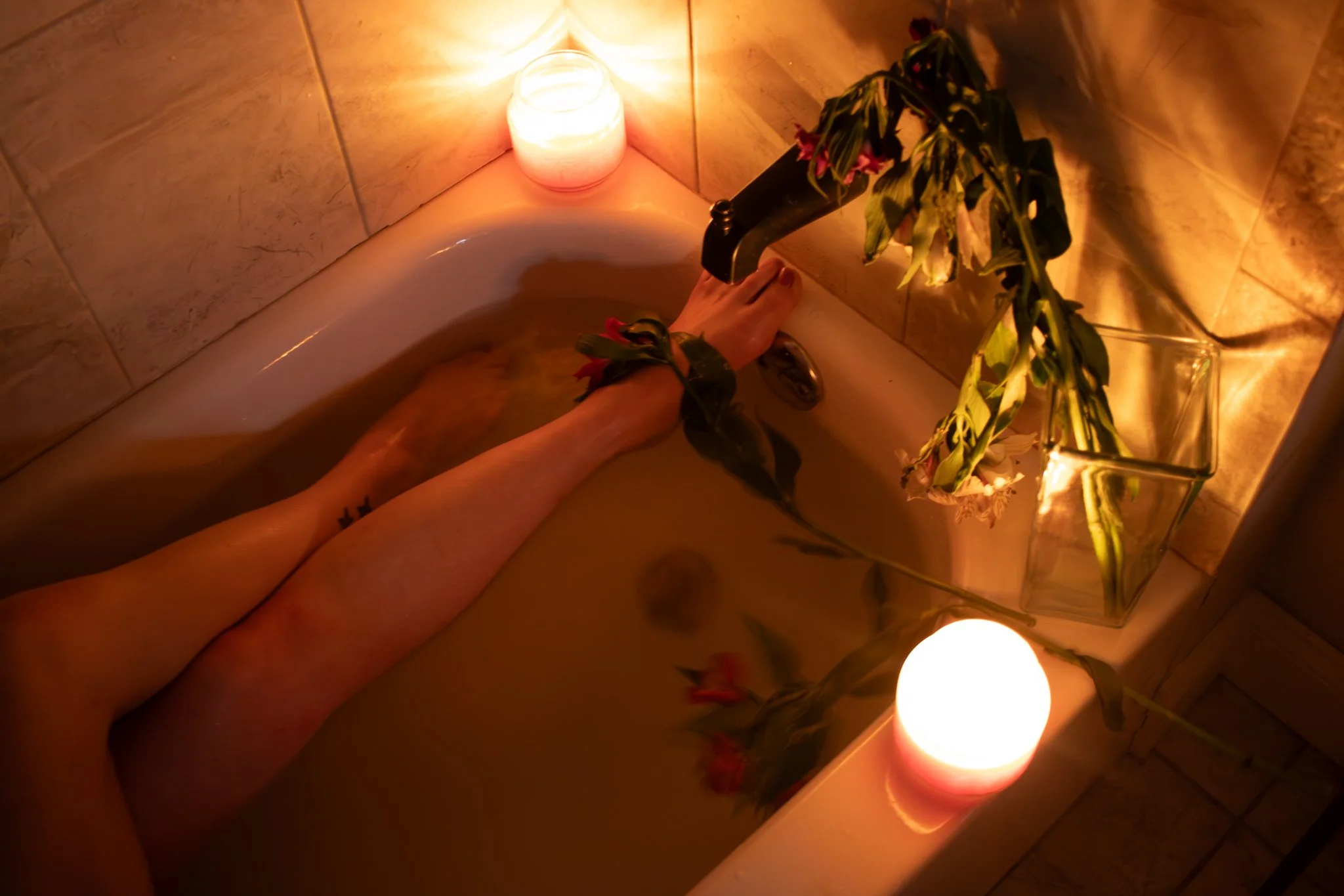 boudoir photo of bare legs in a bathtub in a romantic setting