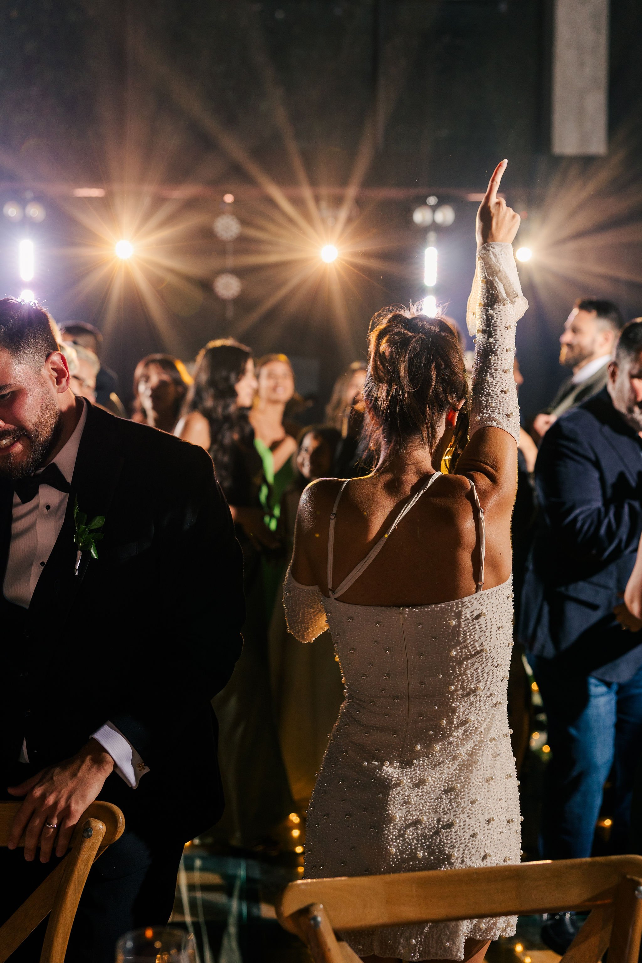 People dancing and enjoying themselves at a party or celebration with bright lights overhead.