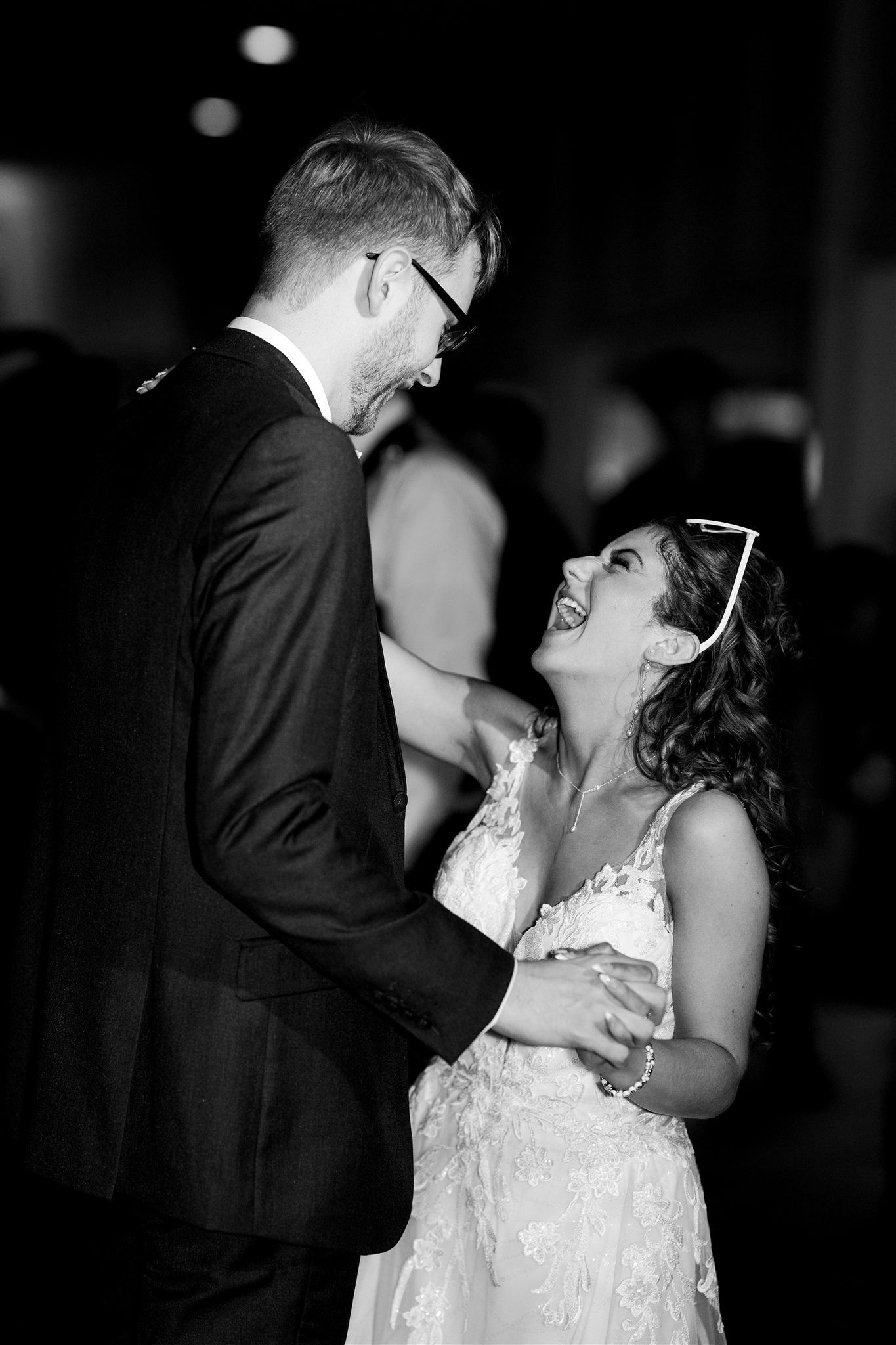 A happy couple dancing, smiling and looking into each other's eyes at their wedding reception.