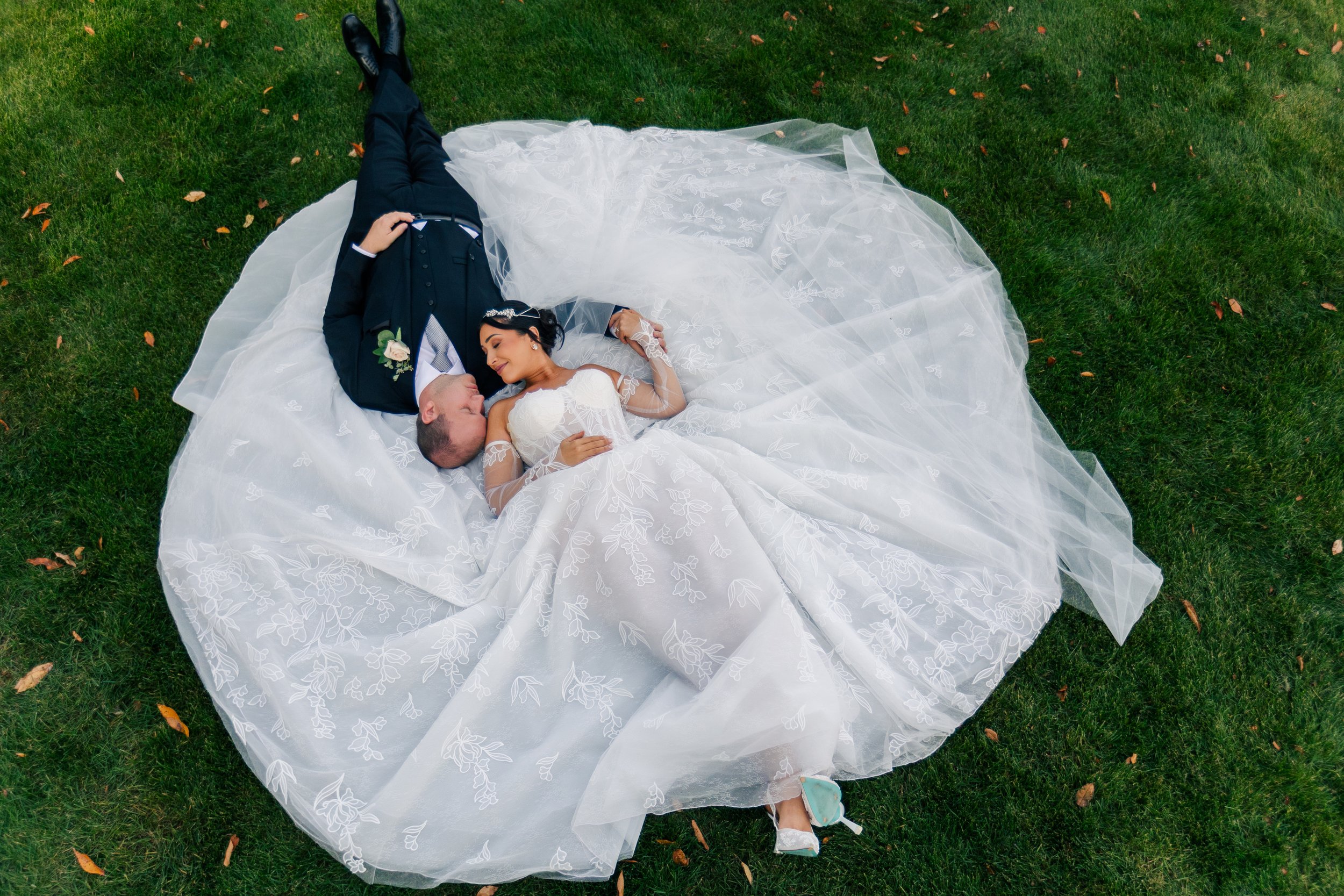 A couple laying on the grass at Venue Bella Giornata in Grand Rapids Michigan embracing.