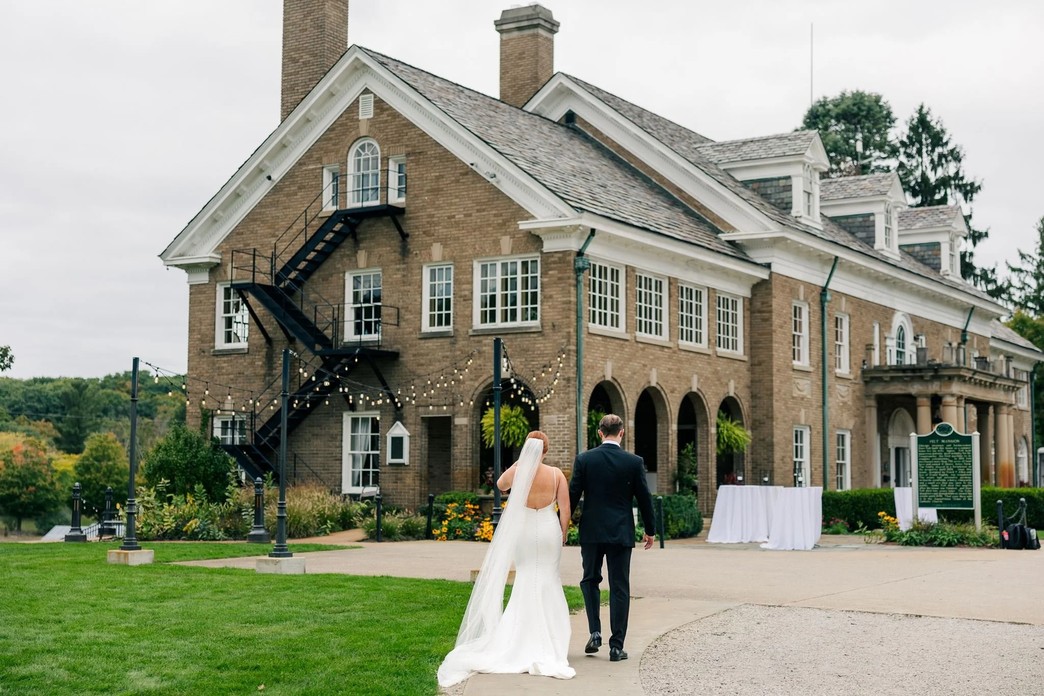 A bride and groom walk into the Felt Estate in Holland, MI after their wedding ceremony.