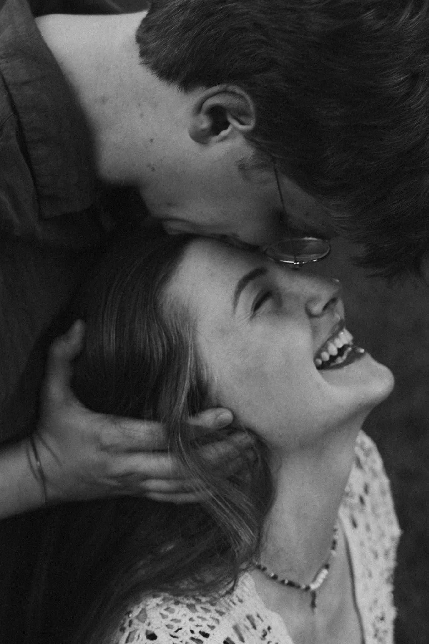 Black and white close up portrait of a couple smiling with forehead kiss