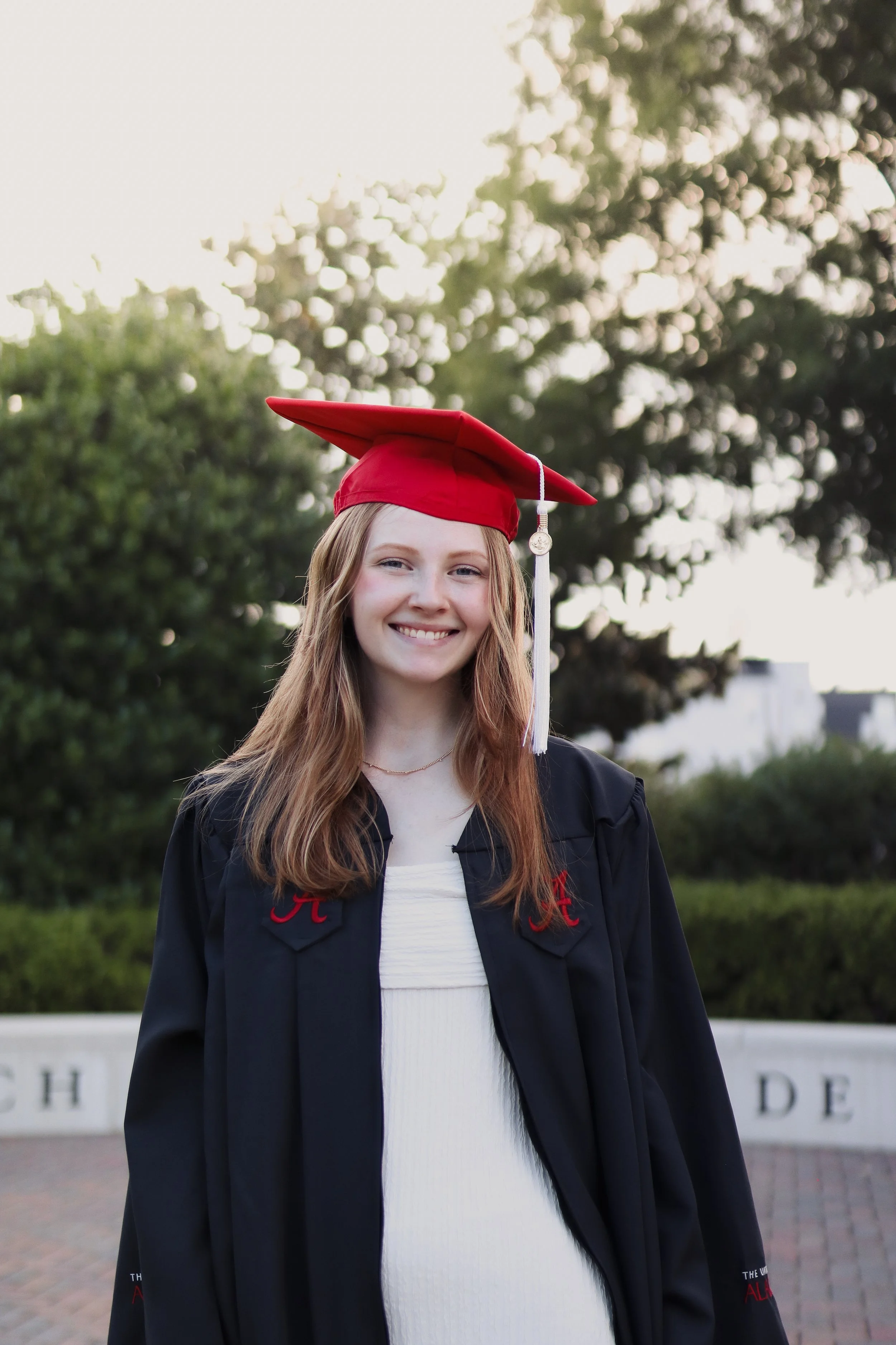 female college graduate Standing outside in cap and gown smiling