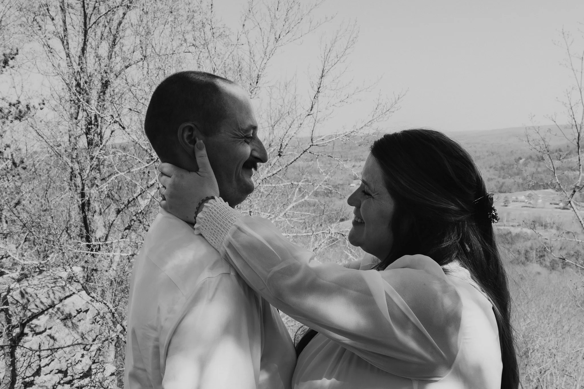 alabama photographer captures intimate playful black and white portrait of bride and groom outside laughing taking portraits at an overlook