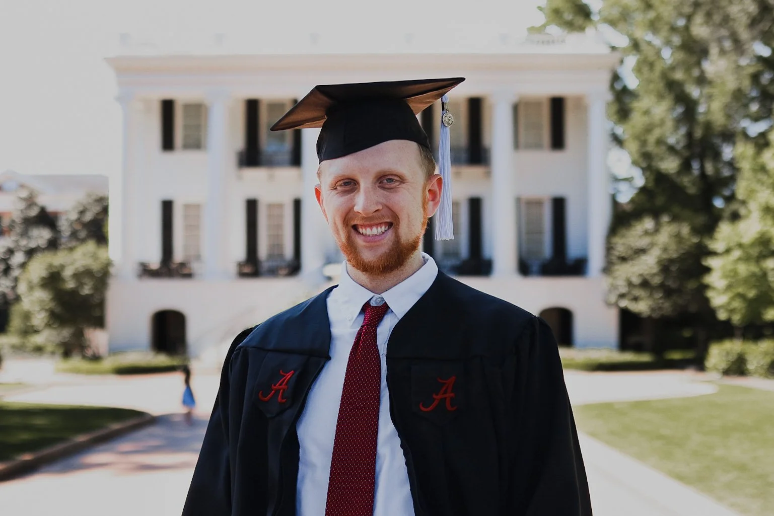 Male college graduate standing outside in black cap and gown