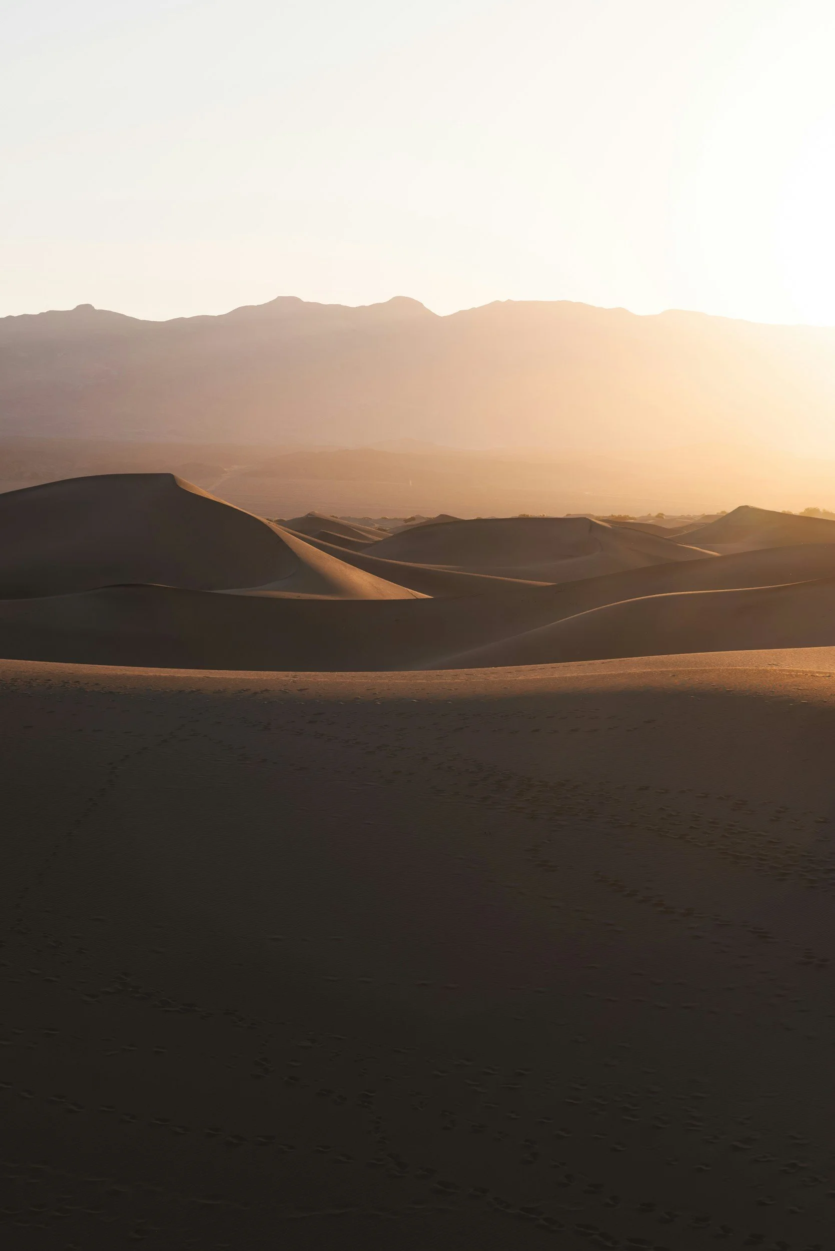 Sand dunes at sunrise with mountains in the background