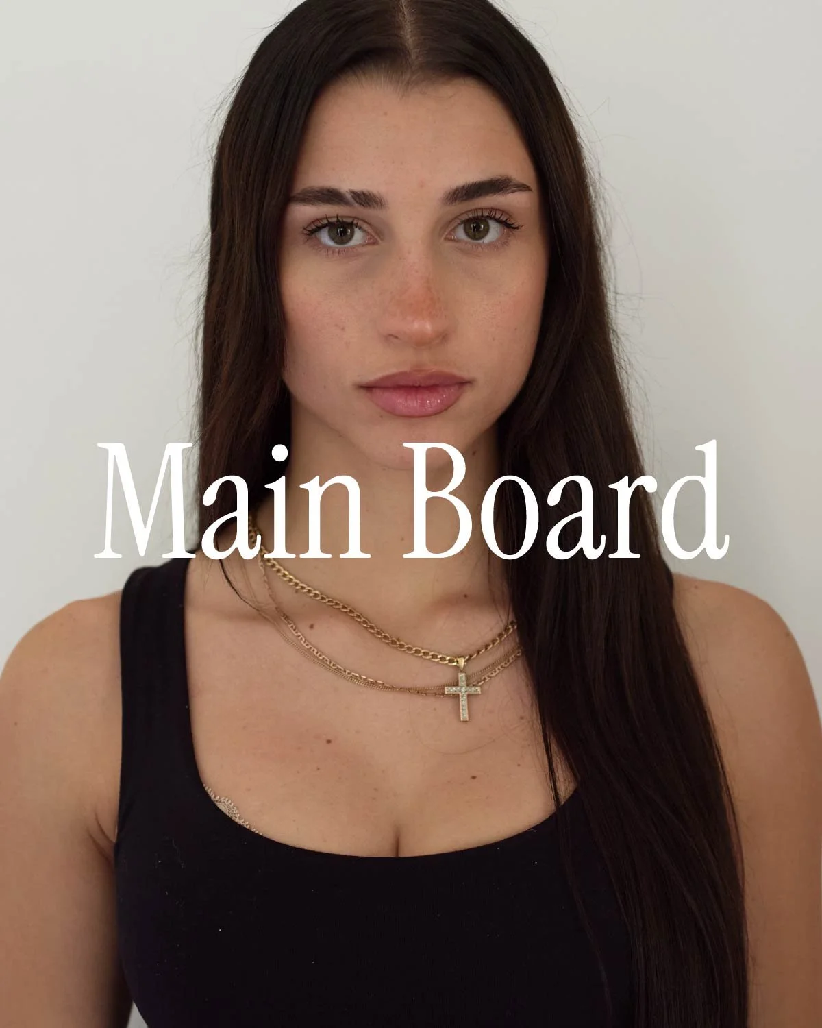 A young woman with long dark hair wearing a black tank top and gold necklaces with a cross pendant, standing against a white background, with the text 'Main Board' overlayed.