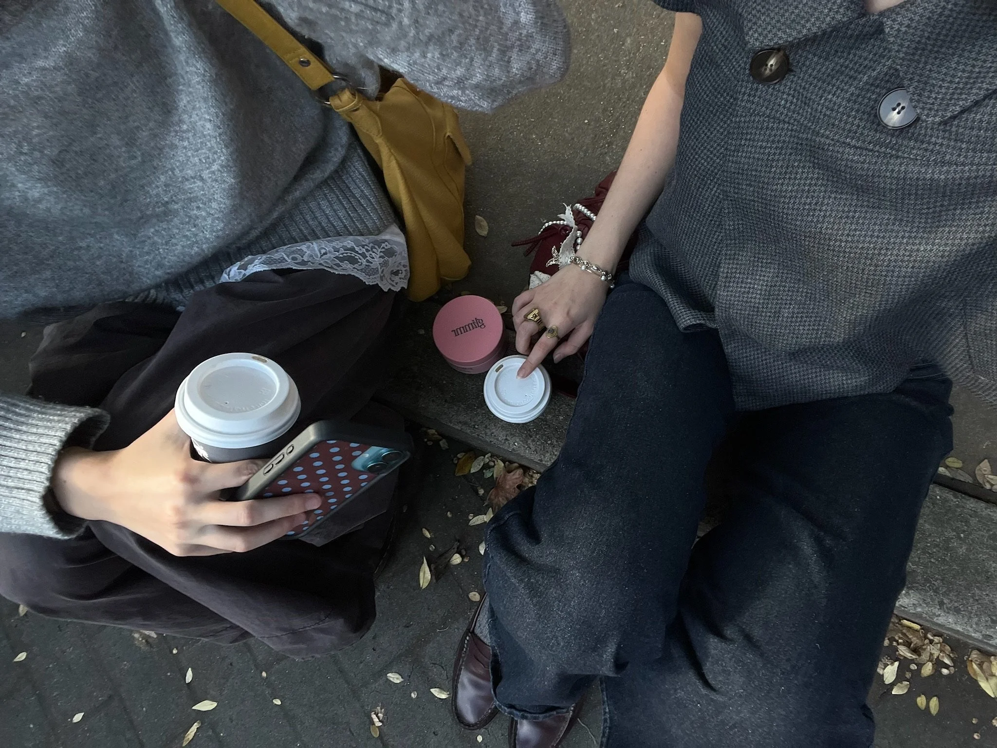 Two people sitting side by side on a city bench with takeaway coffees on a morning date