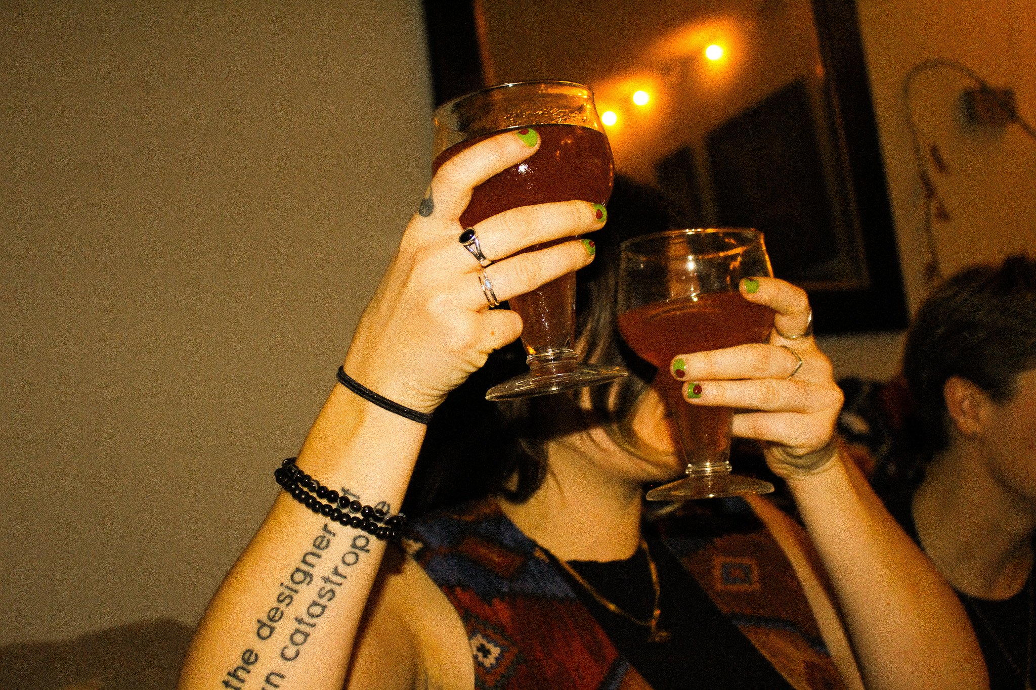 Raising two glasses for a toast in a warmly lit bar on an evening drinks date
