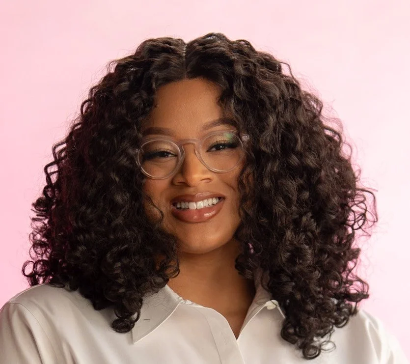 Image of Queer Nourish Founder Taylor with curly hair, clear glasses, and a white button down shirt.