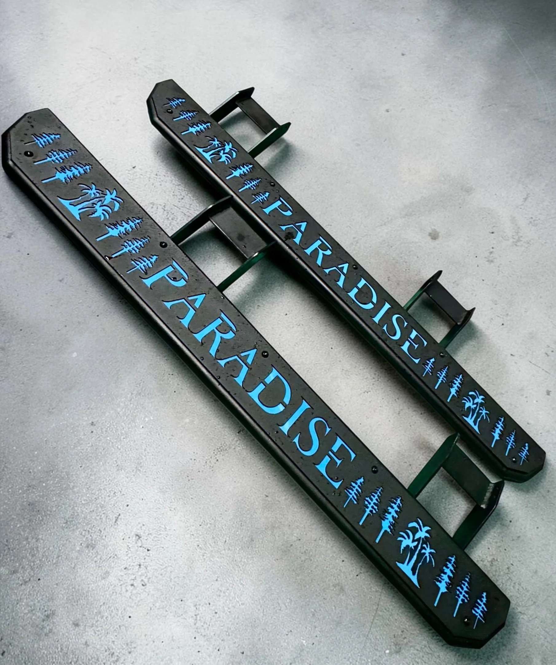 LED illuminated road signs with the text 'IT'S YOUR PARK' and images of palm trees, placed on a gray concrete surface.
