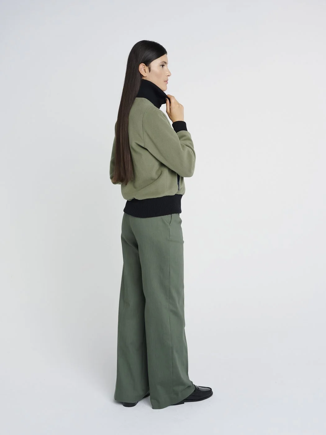Outdoor Jacke in oliv-grün mit hohem Kragen aus Strick und Reißverschlusstaschen, kastig geschnitten.