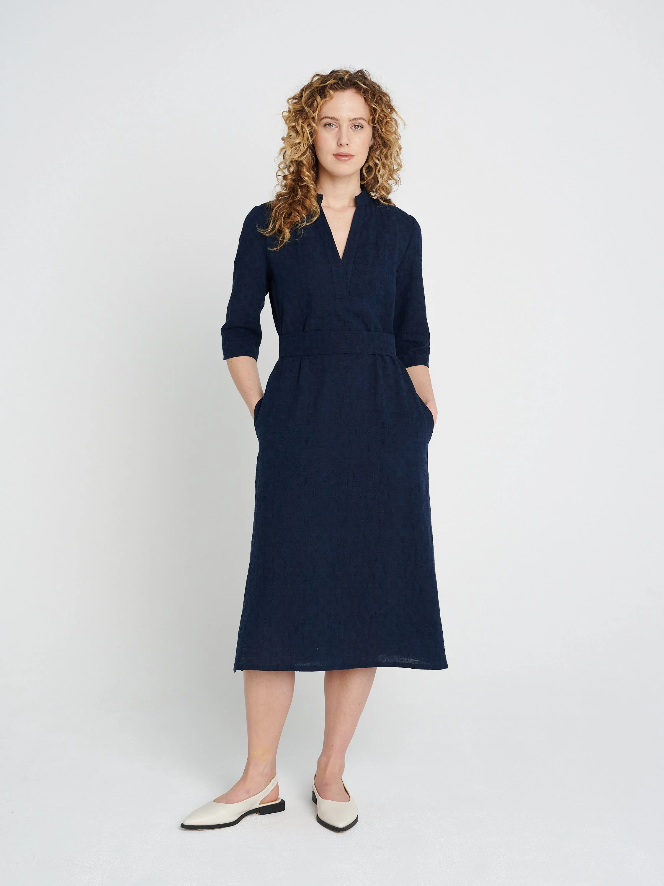 Lässiges, gerade geschnittenes dunkelblaues Kleid mit Tunika-Ausschnitt und dreiviertel-Ärmeln, Schlitzen und Taschen.