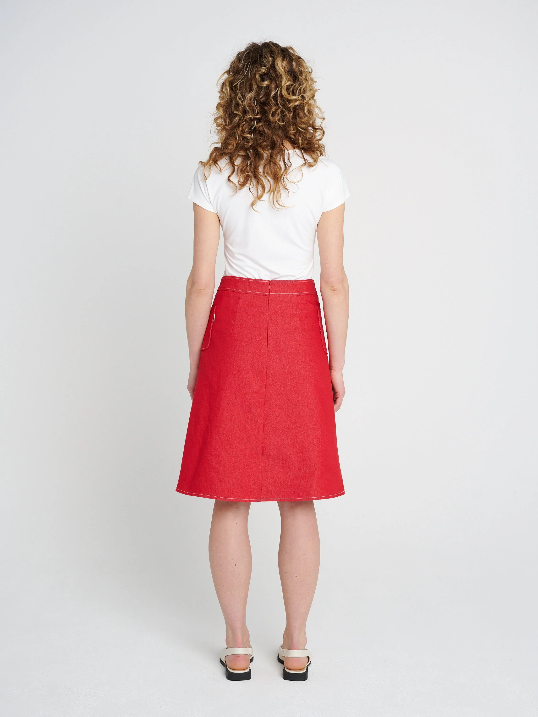 Roter knielanger Jeansrock aus Baumwolle mit weitem Saum, breitem Bündchen und Taschen.