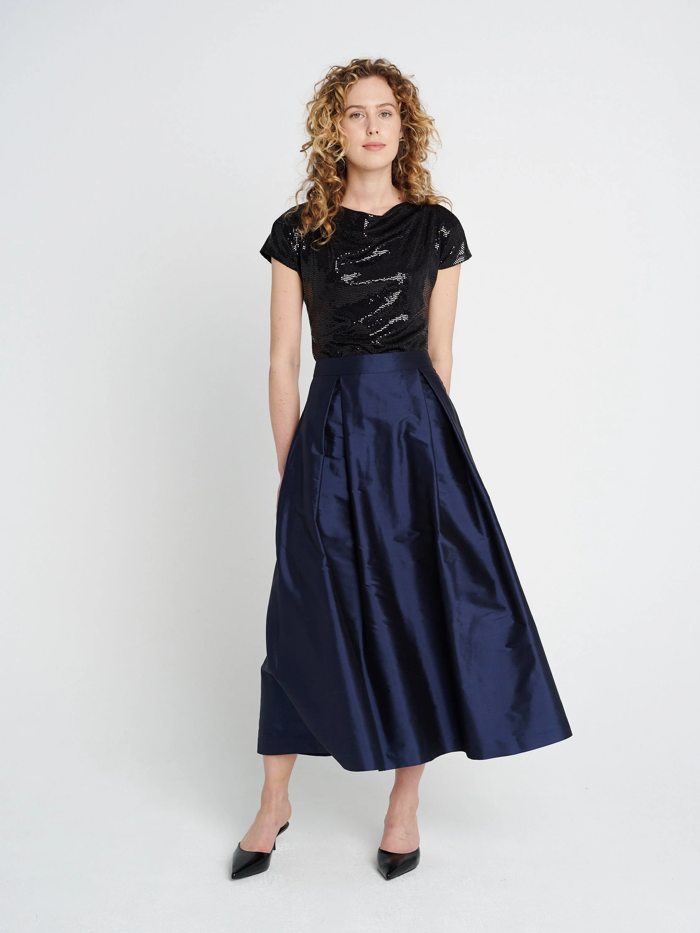 Dunkelblauer Abendrock aus Seide mit großen Falten und Taschen, mittellang.