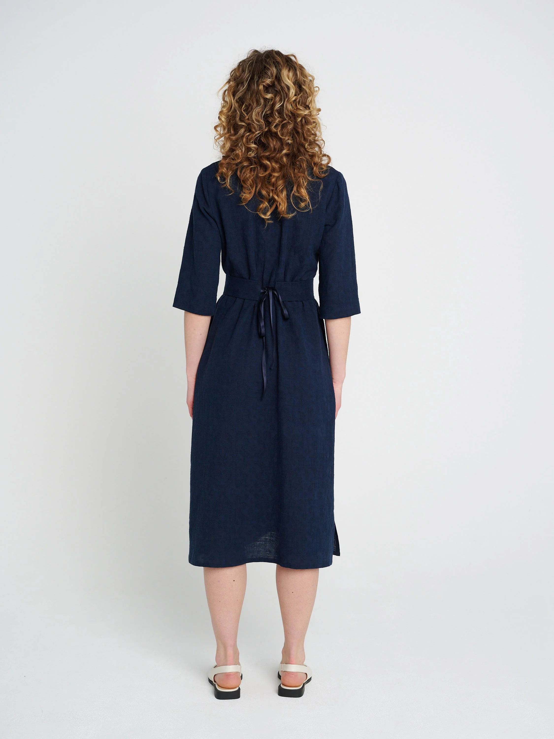 Lässiges, gerade geschnittenes dunkelblaues Kleid mit Tunika-Ausschnitt und dreiviertel-Ärmeln, Schlitzen und Taschen.