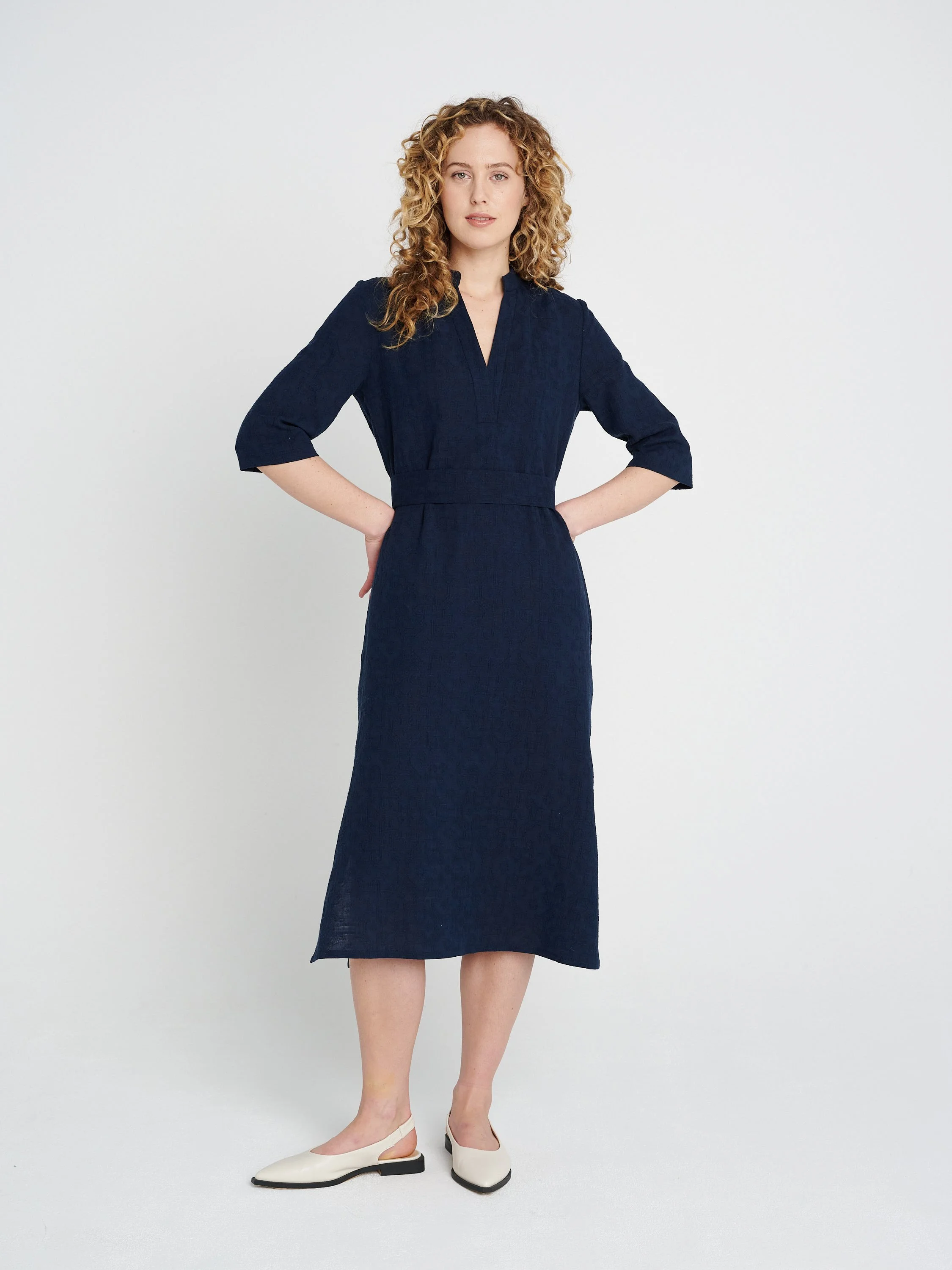 Lässiges, gerade geschnittenes dunkelblaues Kleid mit Tunika-Ausschnitt und dreiviertel-Ärmeln, Schlitzen und Taschen.