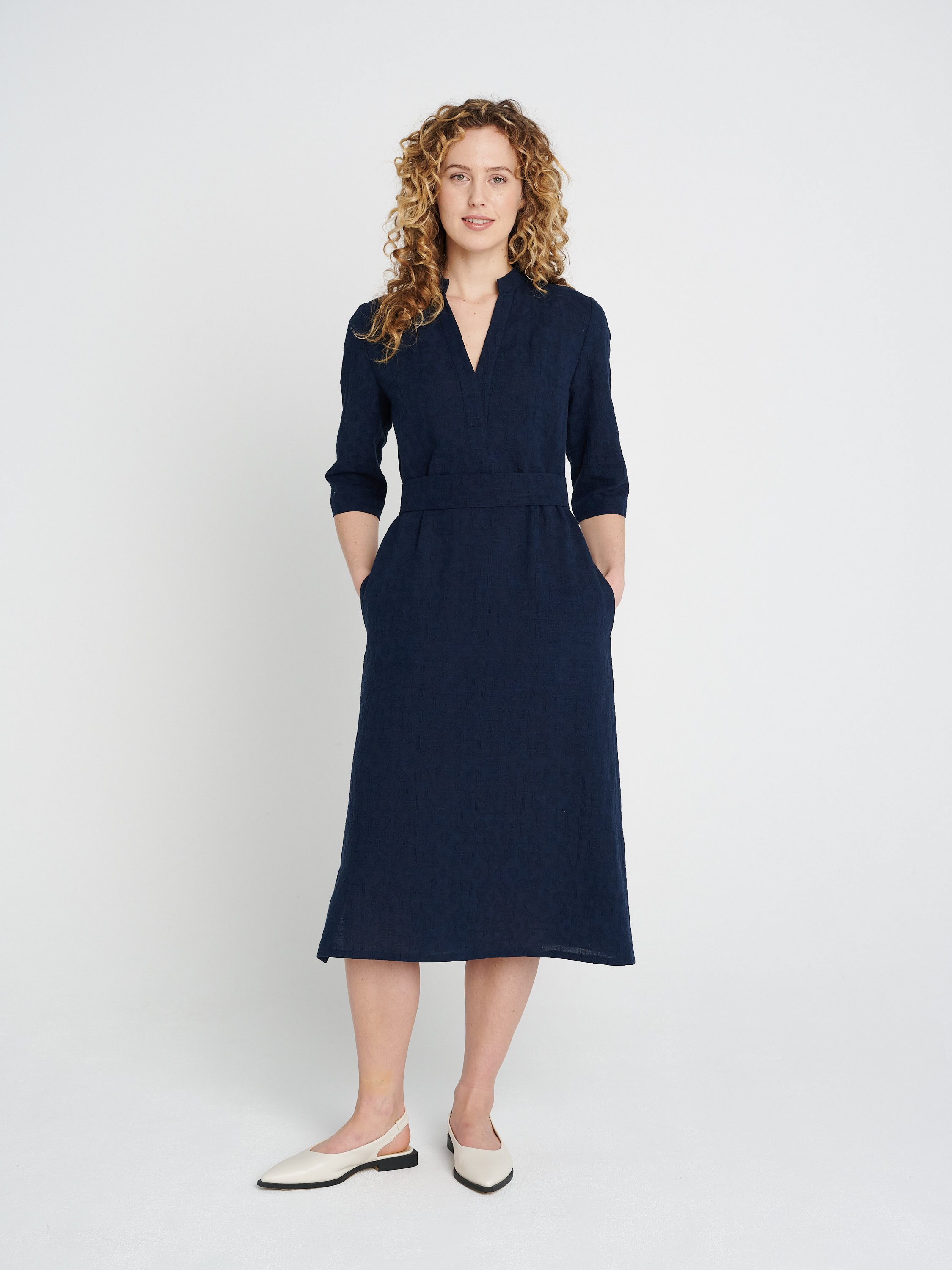 Lässiges, gerade geschnittenes dunkelblaues Kleid mit Tunika-Ausschnitt und dreiviertel-Ärmeln, Schlitzen und Taschen.