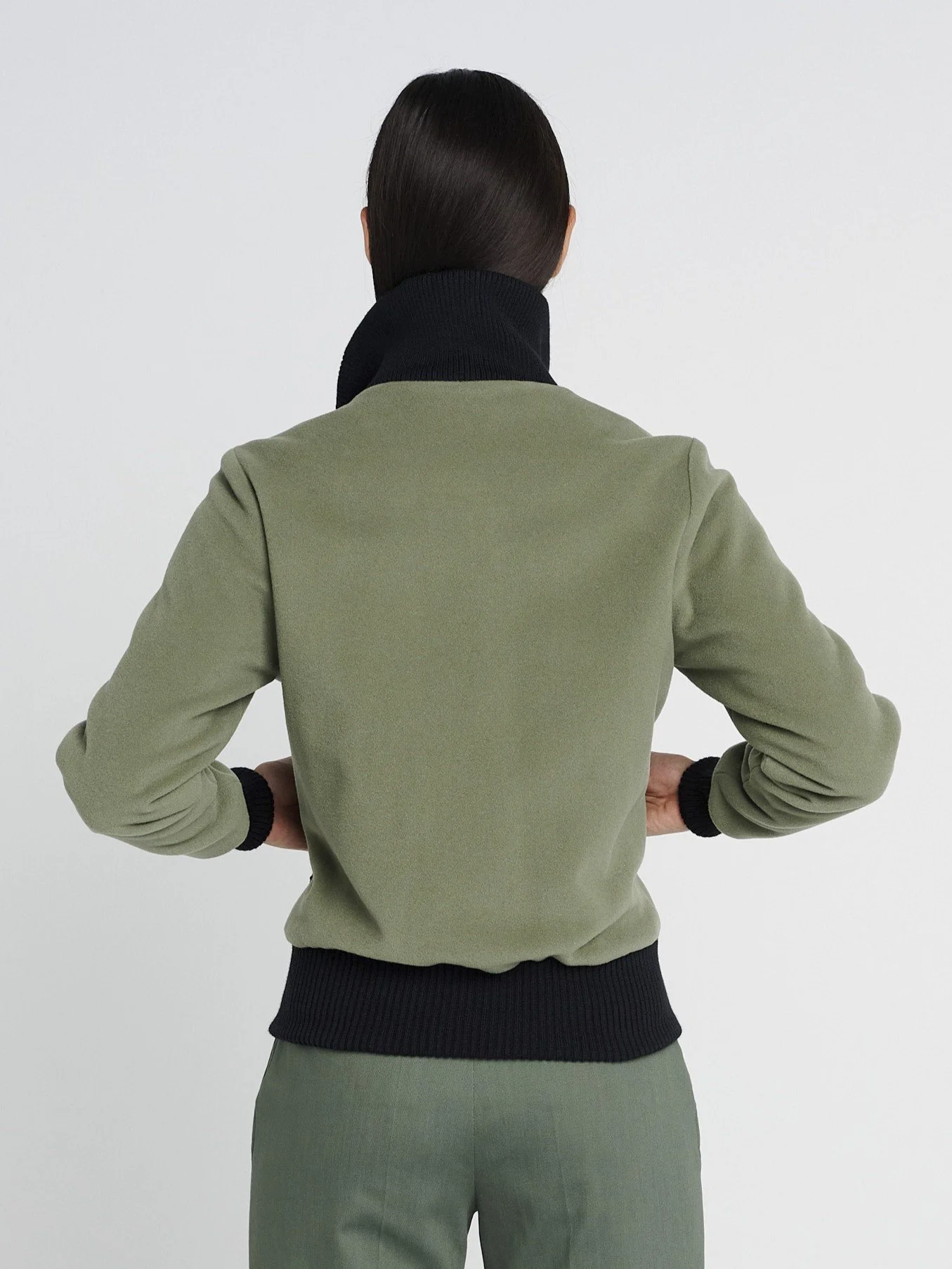 Outdoor Jacke in oliv-grün mit hohem Kragen aus Strick und Reißverschlusstaschen, kastig geschnitten.