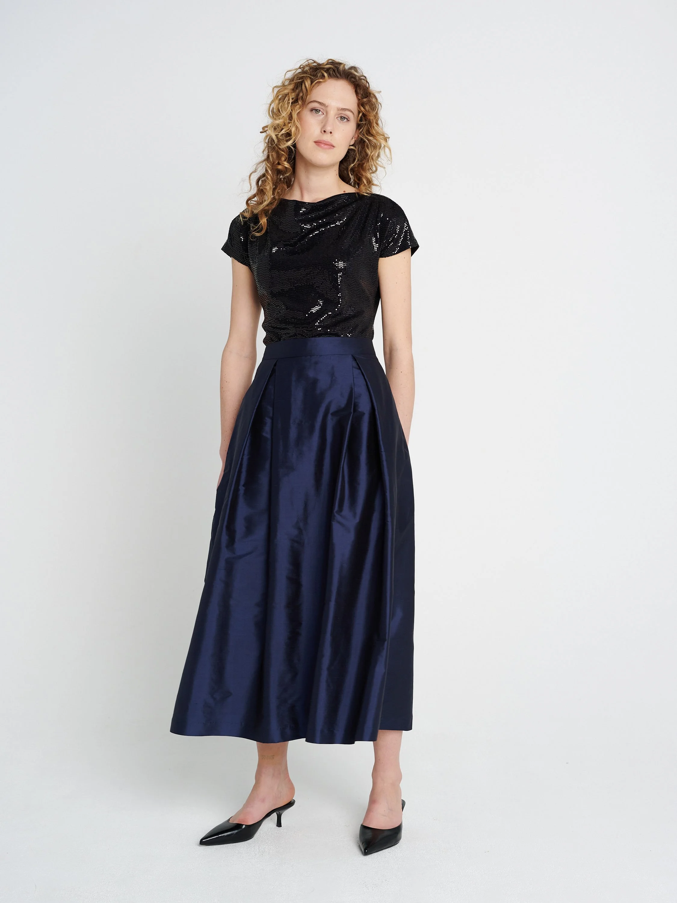 Dunkelblauer Abendrock aus Seide mit großen Falten und Taschen, mittellang.