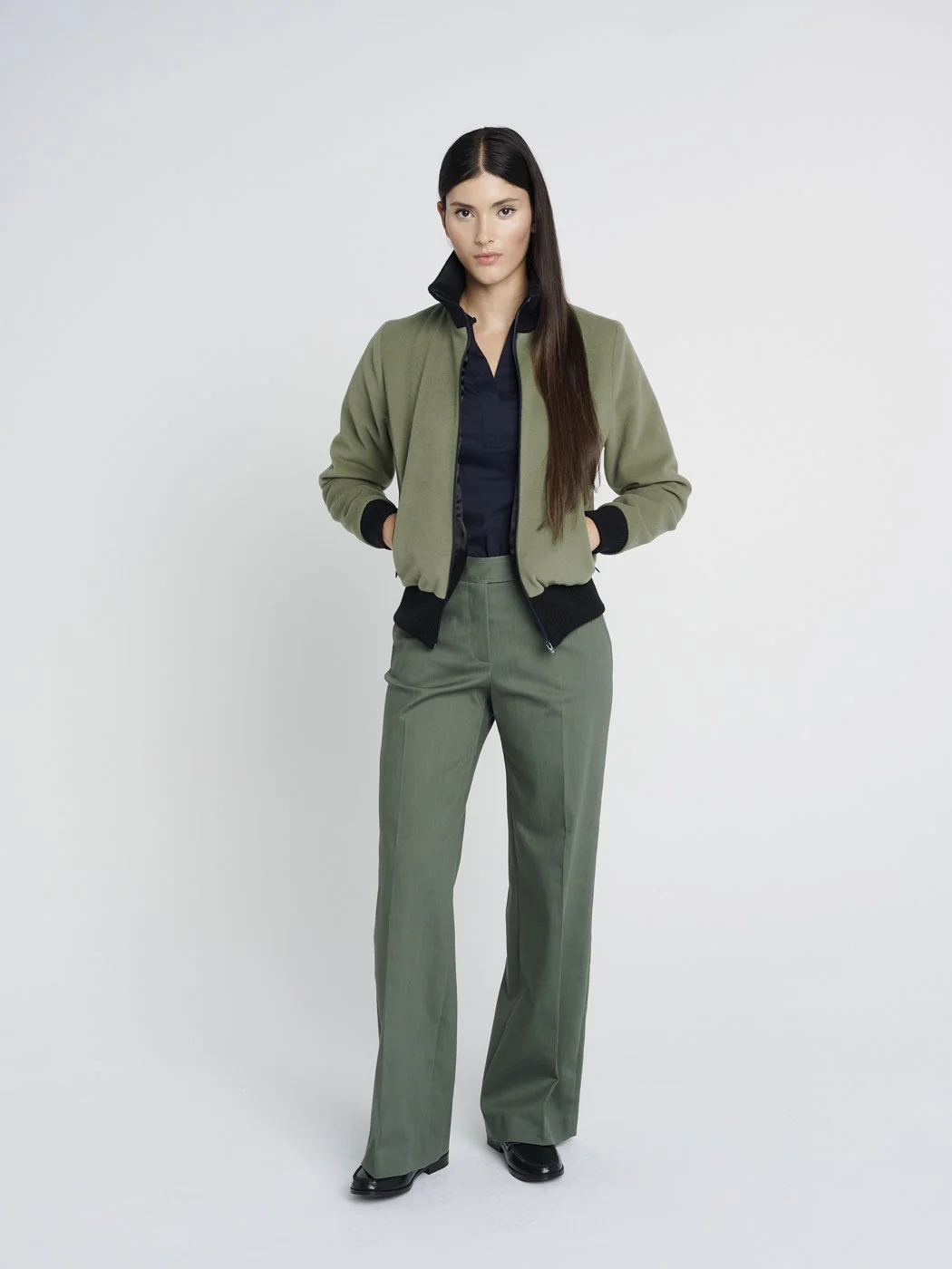 Outdoor Jacke in oliv-grün mit hohem Kragen aus Strick und Reißverschlusstaschen, kastig geschnitten.