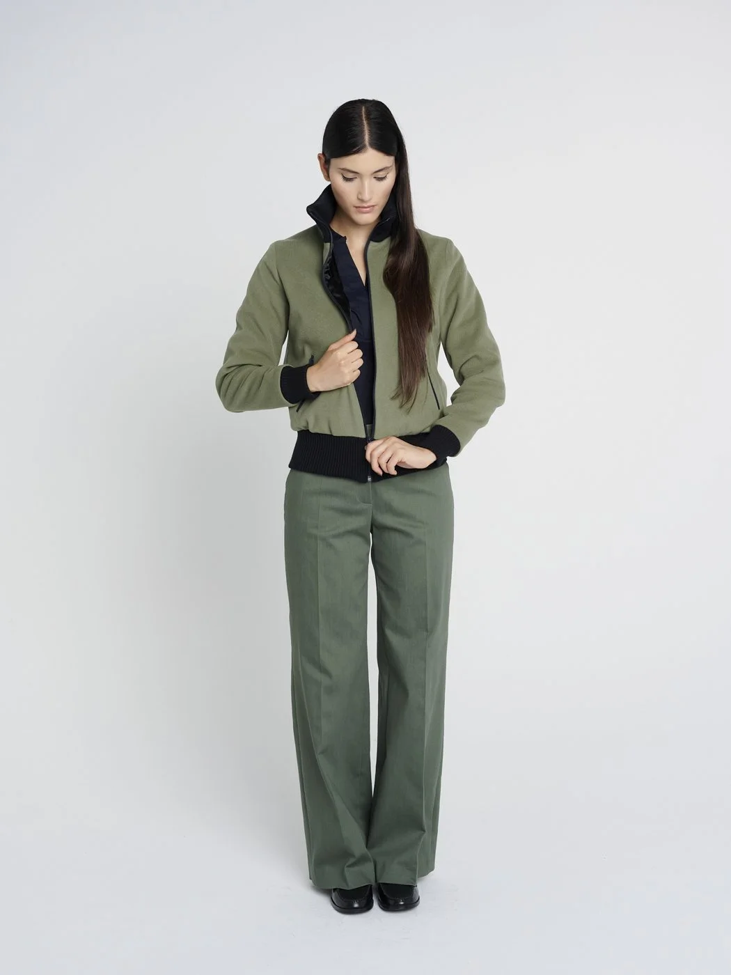 Outdoor Jacke in oliv-grün mit hohem Kragen aus Strick und Reißverschlusstaschen, kastig geschnitten.