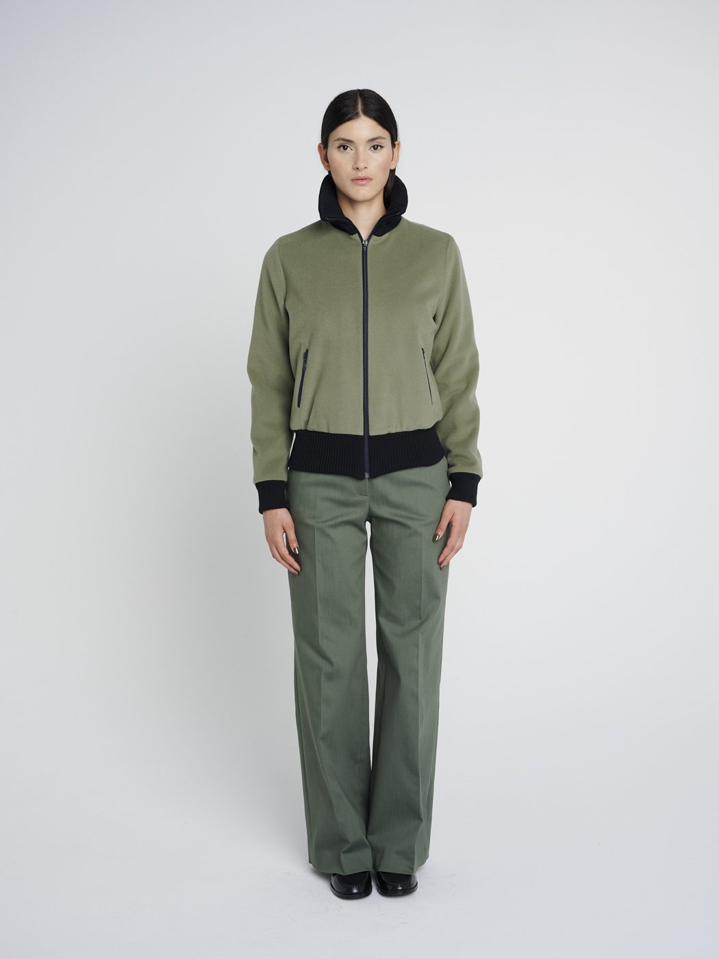 Outdoor Jacke in oliv-grün mit hohem Kragen aus Strick und Reißverschlusstaschen, kastig geschnitten.