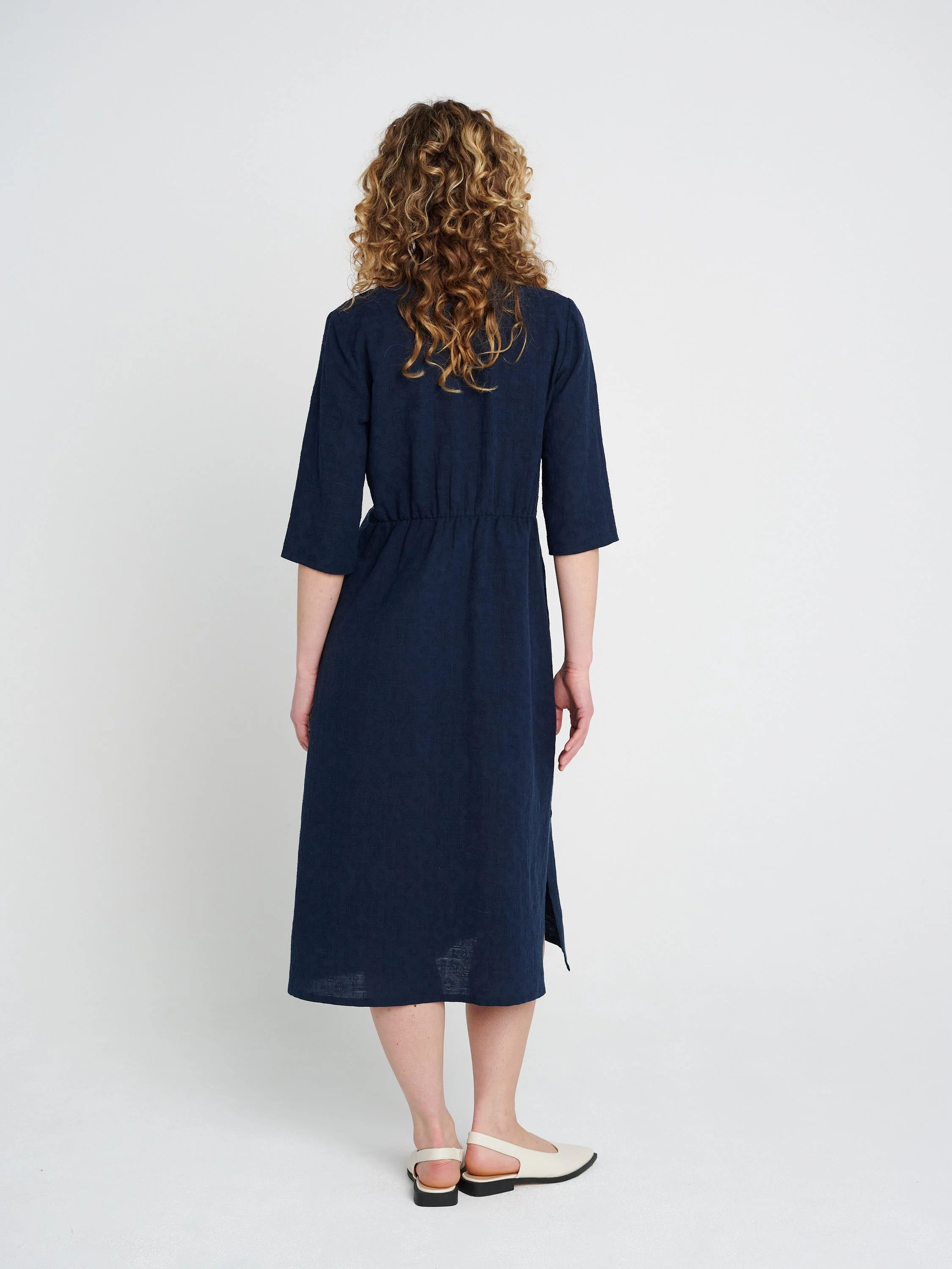 Lässiges, gerade geschnittenes dunkelblaues Kleid mit Tunika-Ausschnitt und dreiviertel-Ärmeln, Schlitzen und Taschen.