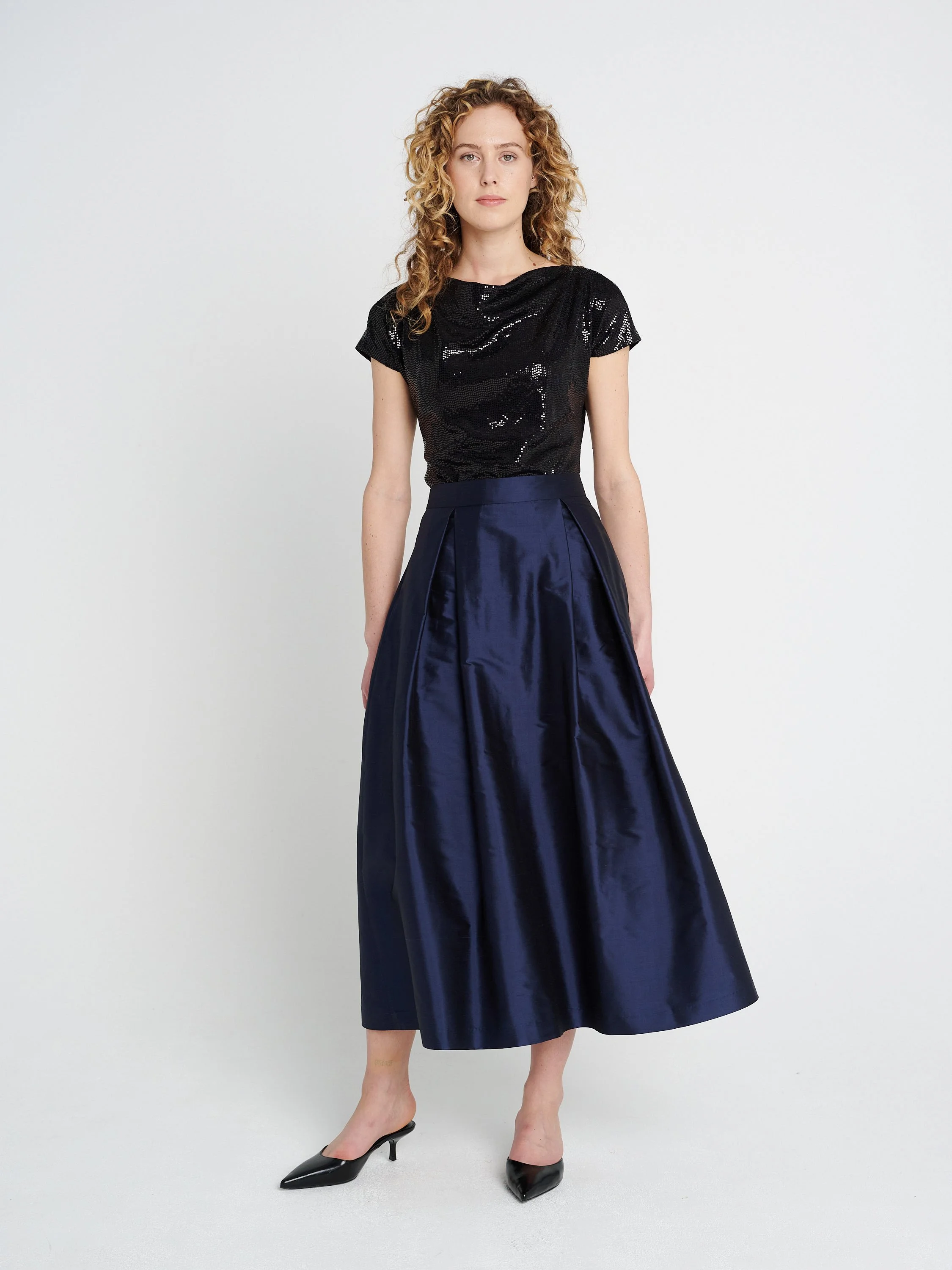 Dunkelblauer Abendrock aus Seide mit großen Falten und Taschen, mittellang.