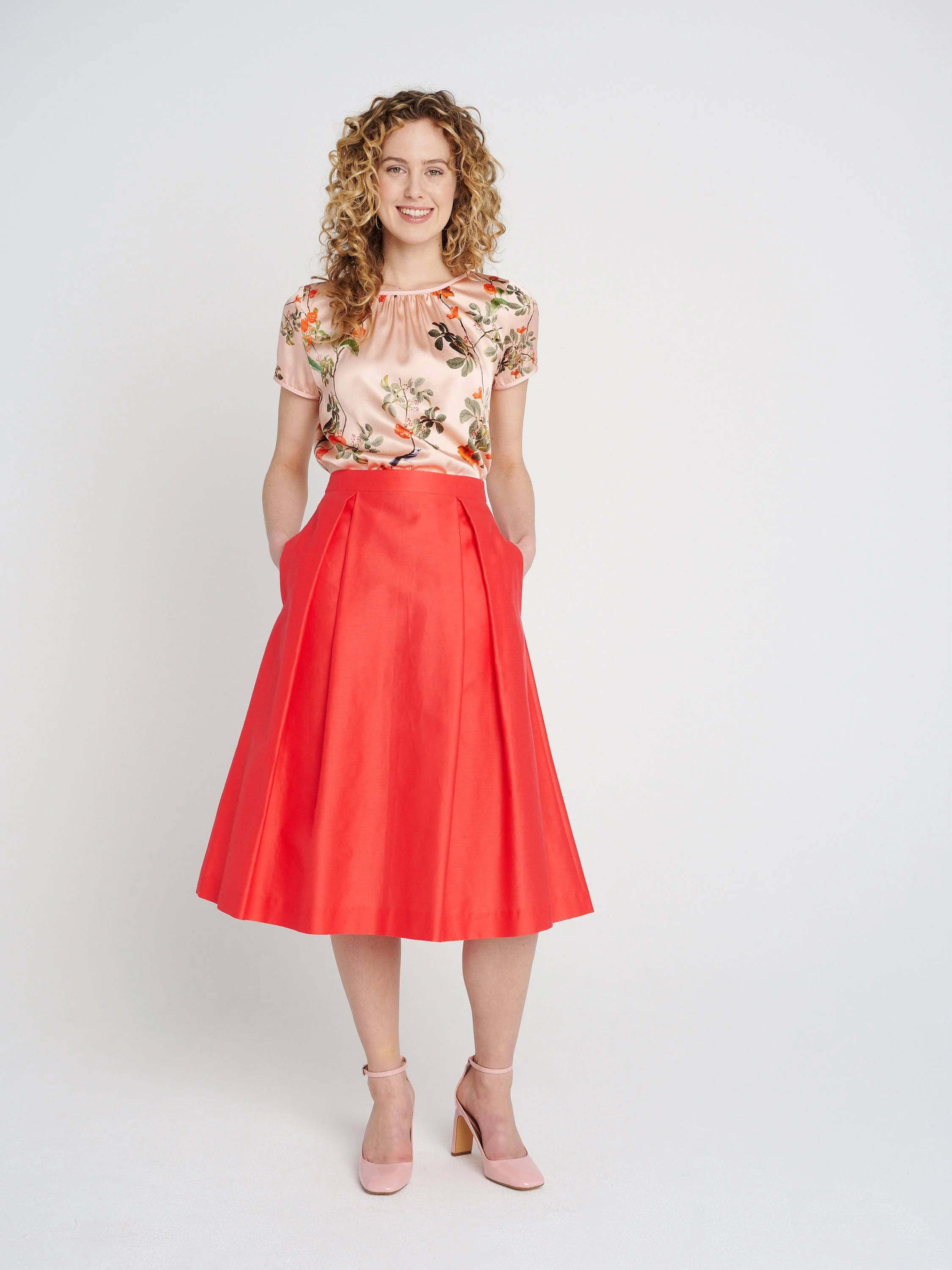 A-Liniger Sommerrock in orange-pink mit Taschen und Kellerfalten, halblang.