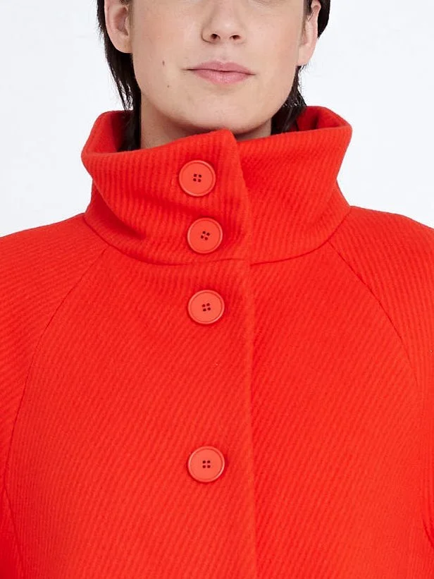 warmer, lockerer, knielanger Designermantel aus korallfarbener Wolle mit Stehkragen und Knöpfen