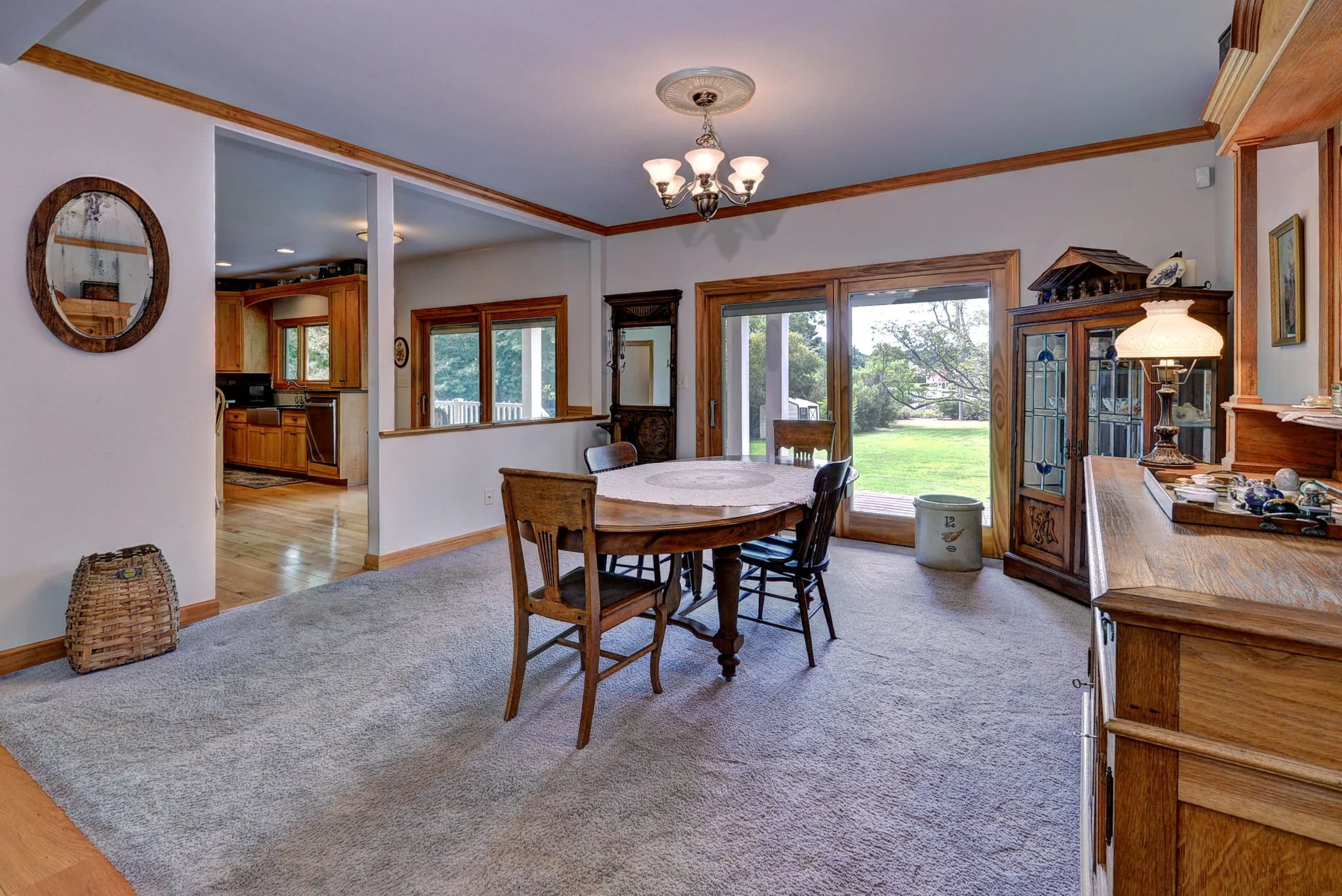 Dining room with wooden furniture, sliding glass door opening to backyard, and window views of greenery.