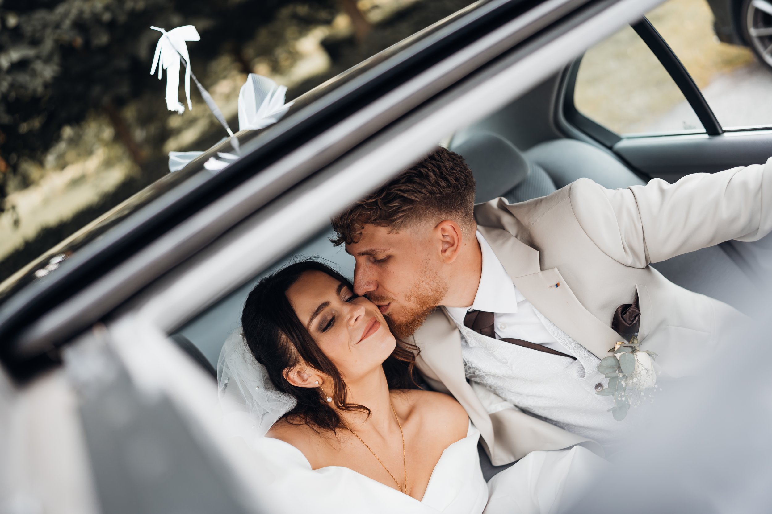 Braut und Bräutigam in Hochzeitsauto, intimen Kuss, glückliches Paar, Hochzeitskleidung, Autodekoration, romantische Stimmung