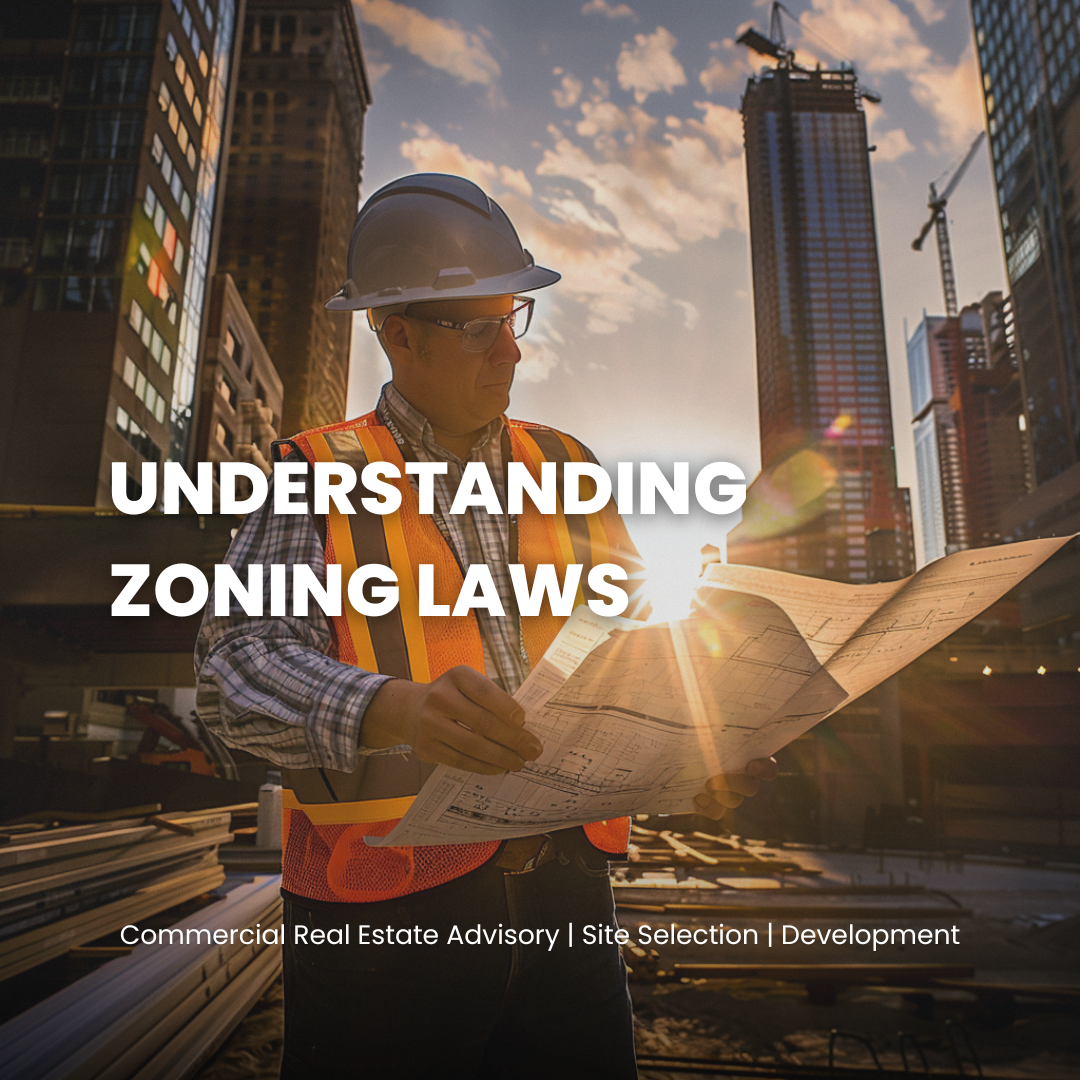 A construction worker in a hard hat and safety vest reviewing blueprints at a construction site in a city during sunset, with tall buildings and clouds in the background.