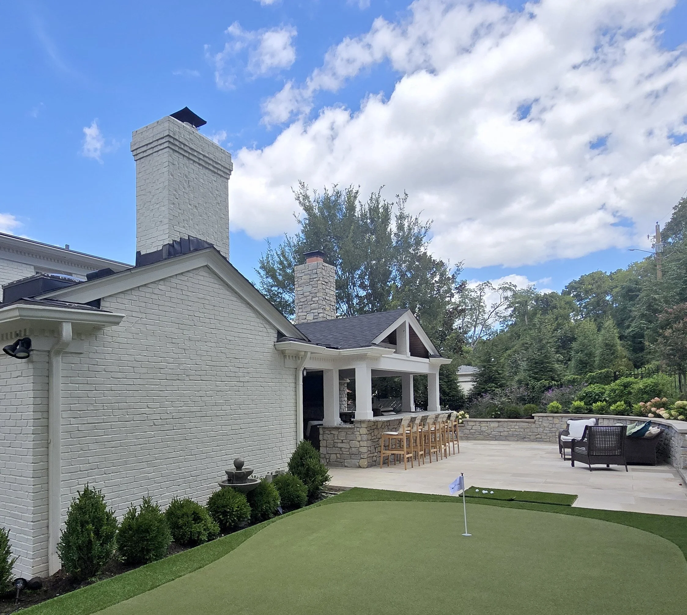 Outdoor fireplace, wood burning fireplace, outdoor kitchen, large format limestone pavers, outdoor bar seating, putting green, retaining wall