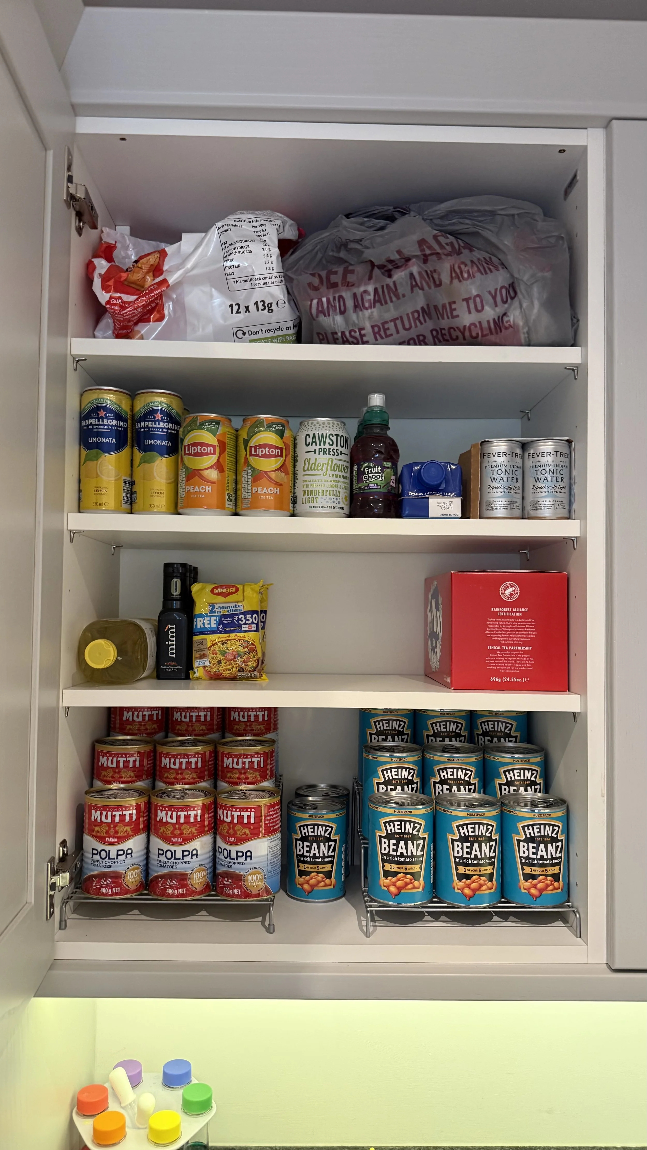 Kitchen cabinet stocked with canned soups, tea, soda, and other pantry items.