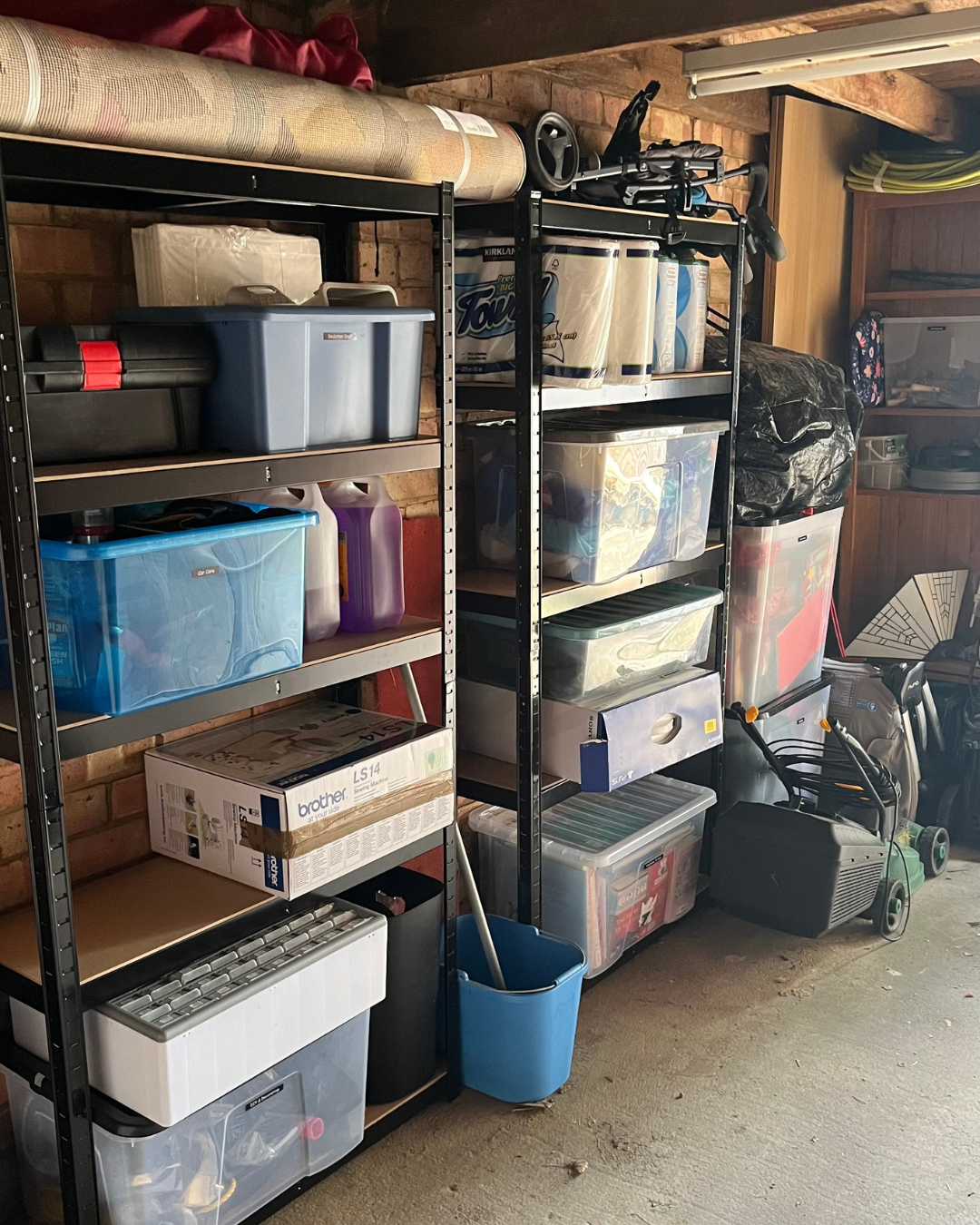 Garage storage with multiple shelves holding bins, boxes, cleaning supplies, and household items.