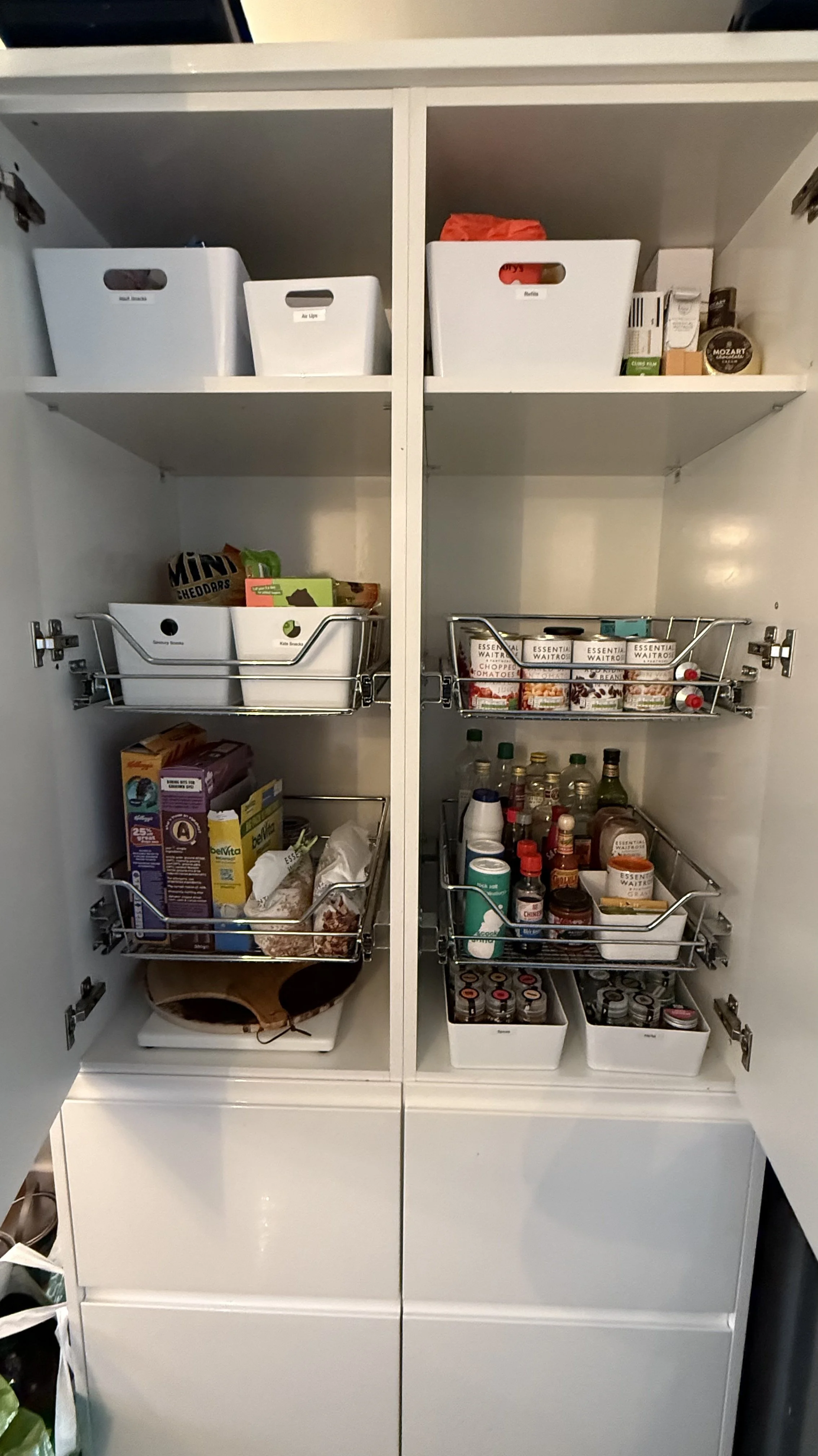 Open kitchen cabinet with shelves storing food, bottles, and containers.