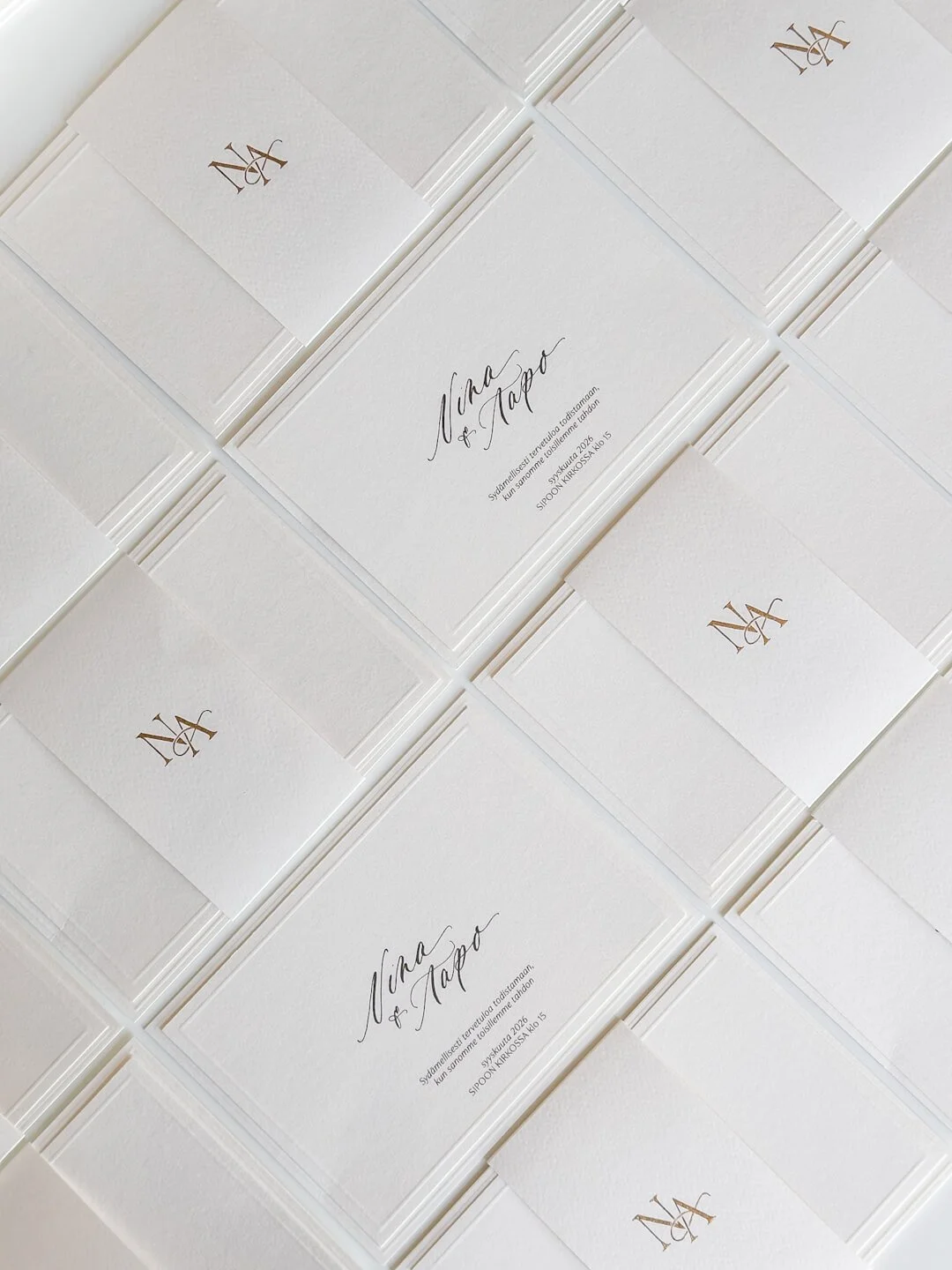 Klassiset kokovalkoiset hääkutsut elegantilla kalligrafialla ja kultaisella monogrammilla.