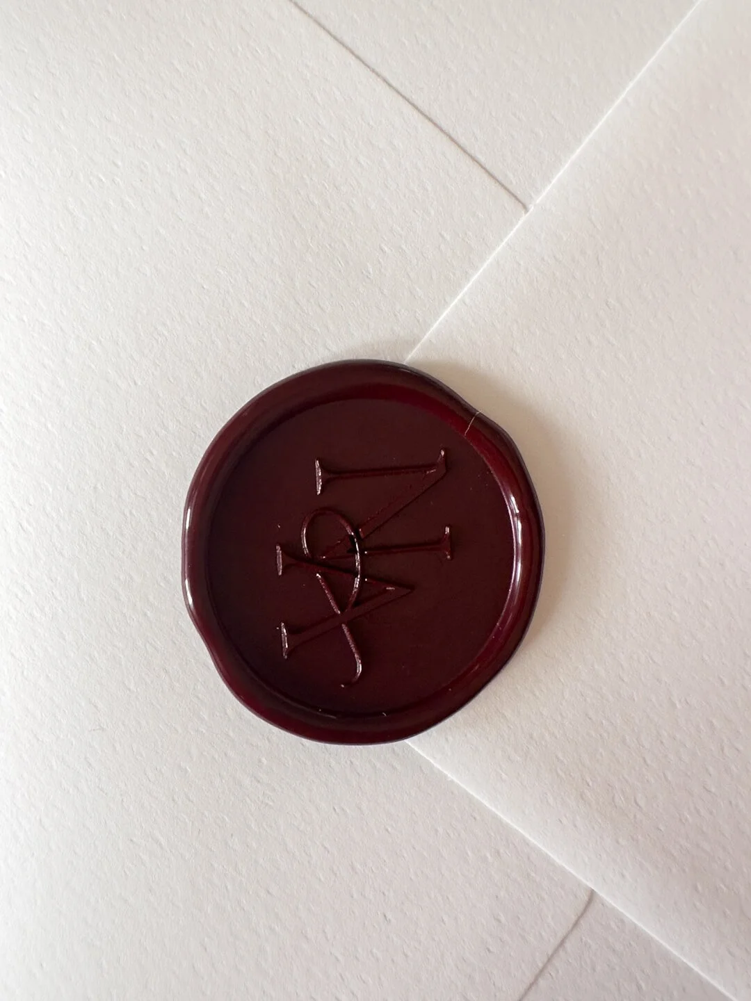Viininpunainen sinetti elegantilla monogrammilla kirjekuoressa.
