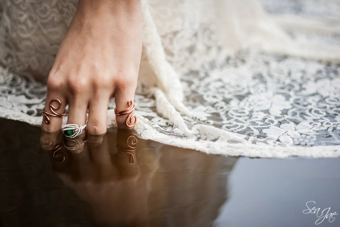 delicate hand in water wearing handmade wire wrapped rings
