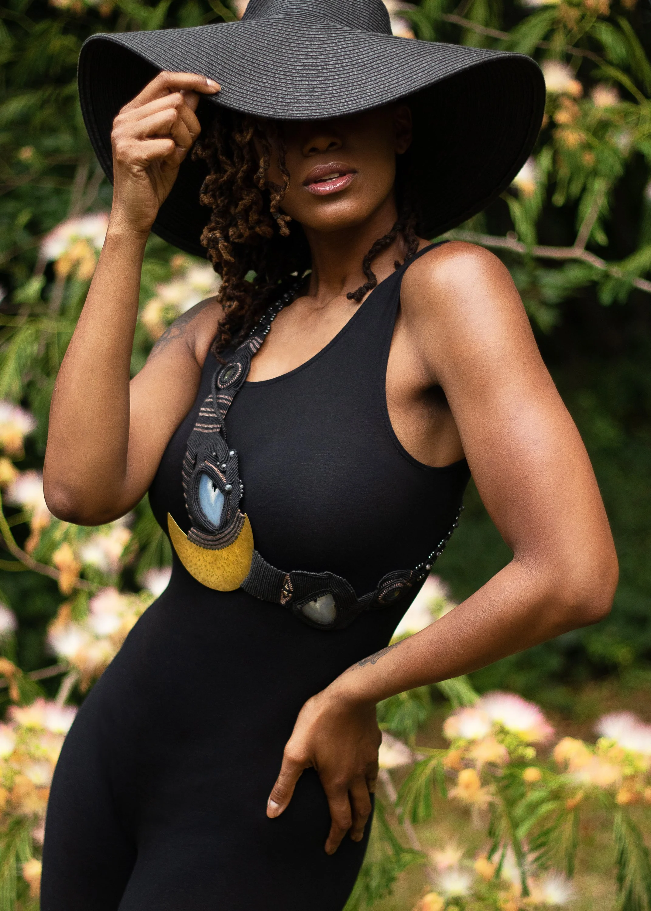 beautiful black woman posing with hat and elaborate sash