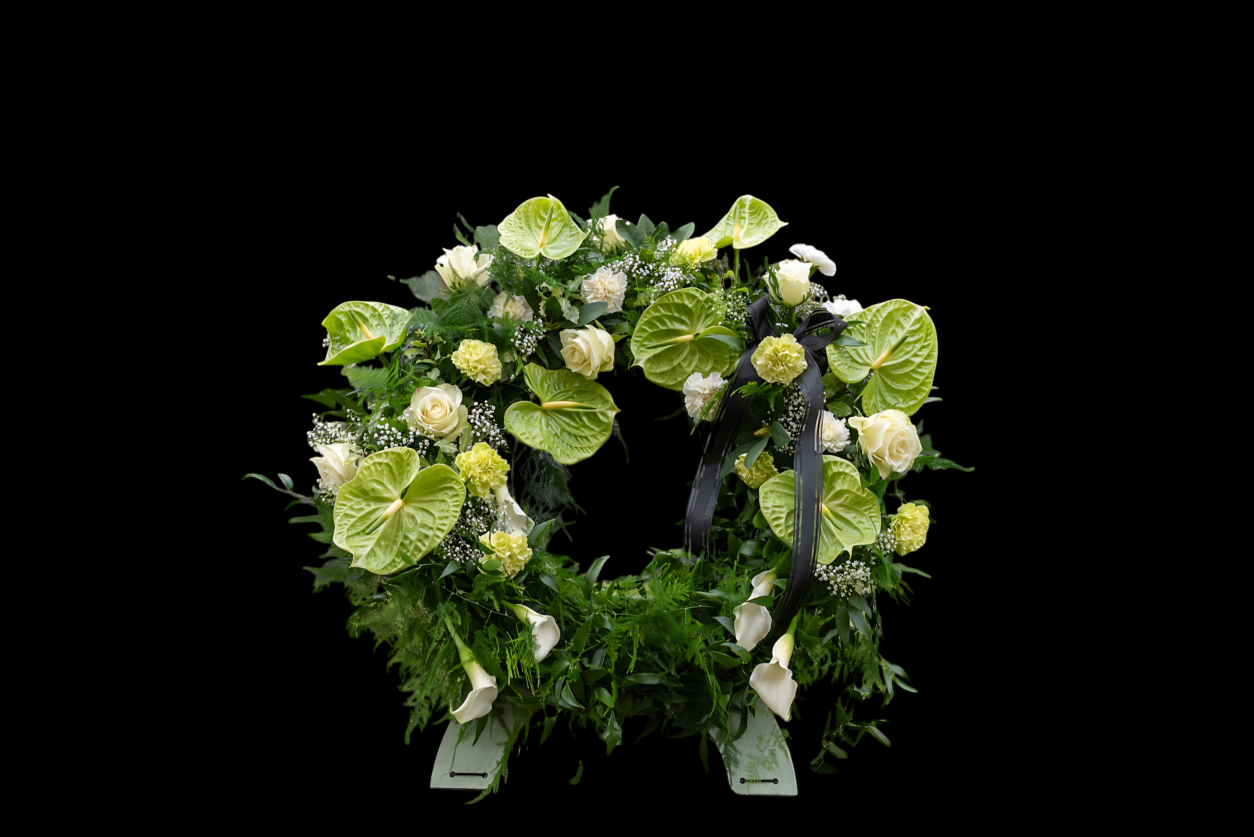 White floral wreath with calla lilies, roses, anthuriums, and greenery on a black background.