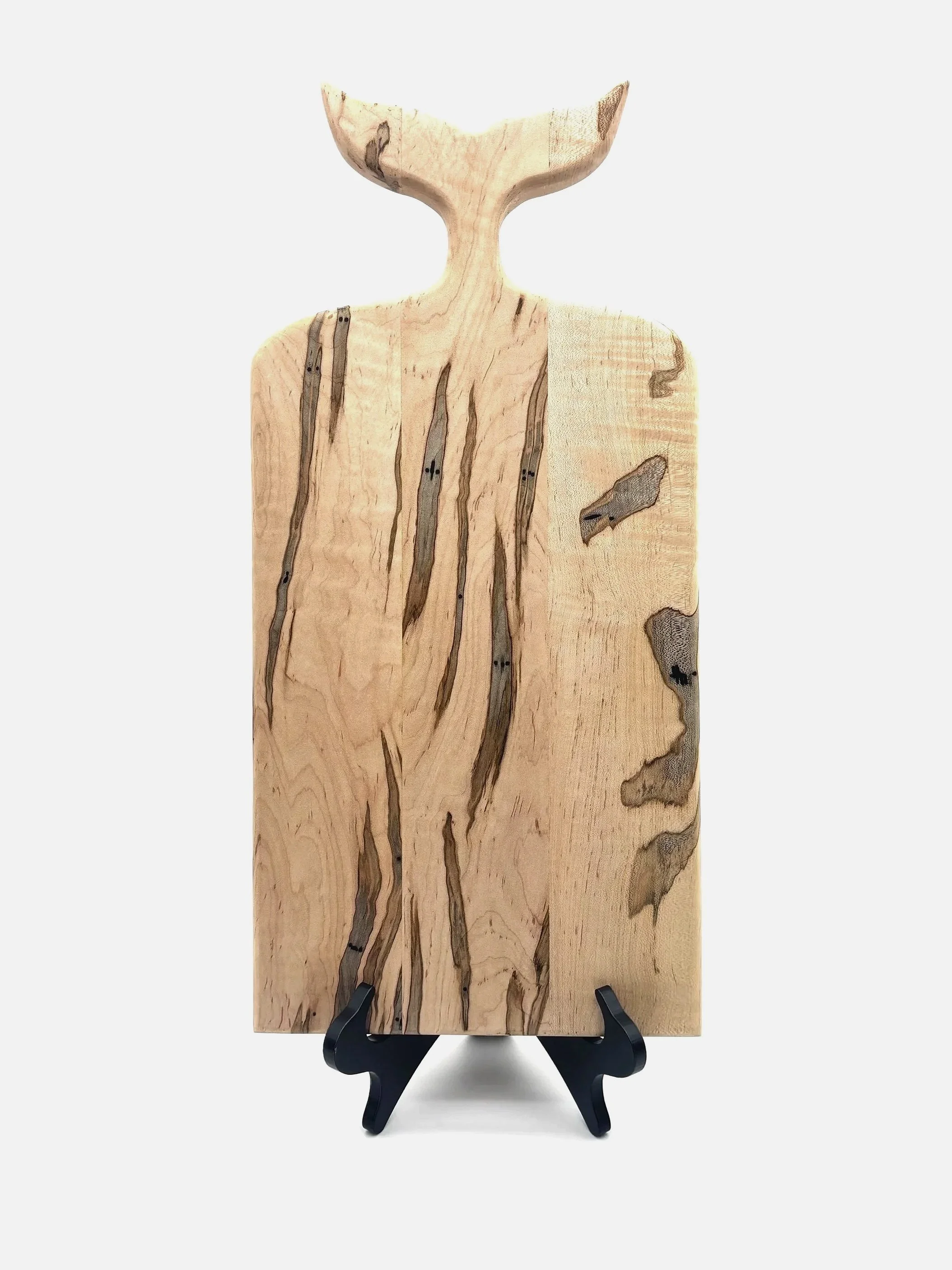 A whale tail shaped cutting or serving board made from ambrosia maple